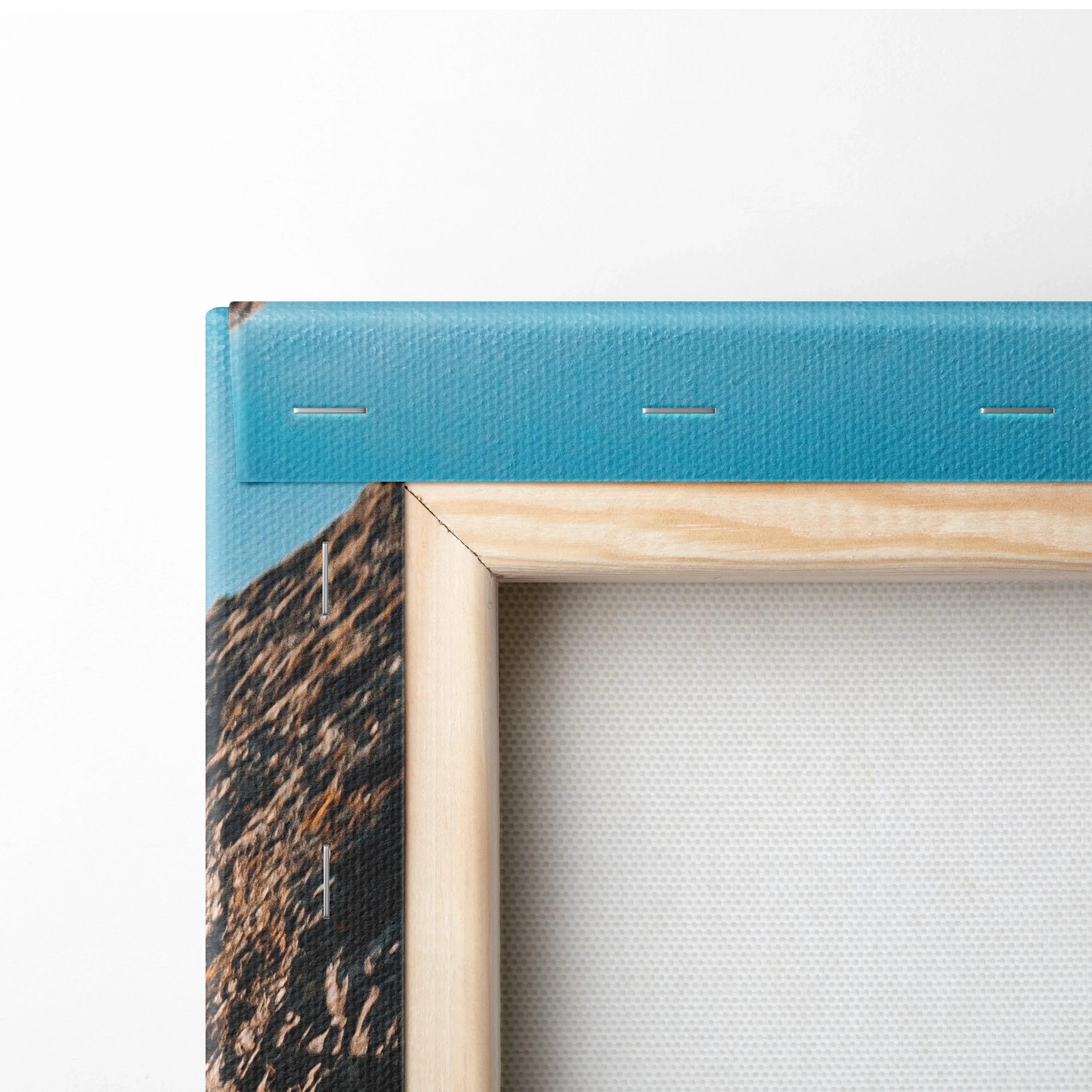 Close-up of wooden frame corner with blue fabric-wrapped canvas featuring printed waterfall and rocky landscape details.