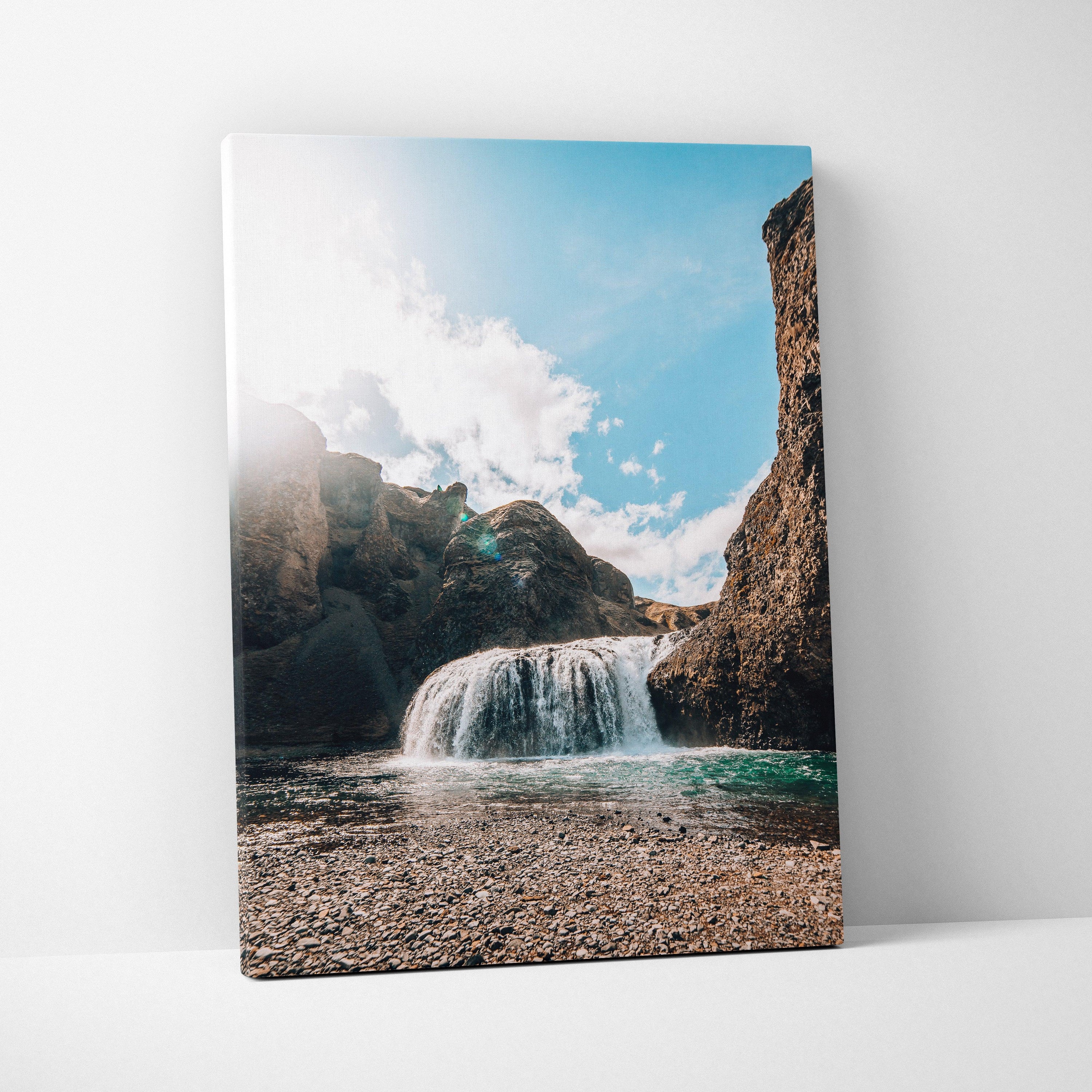 Canvas wall art featuring a vivid Icelandic waterfall with rocky cliffs and bright blue sky background.