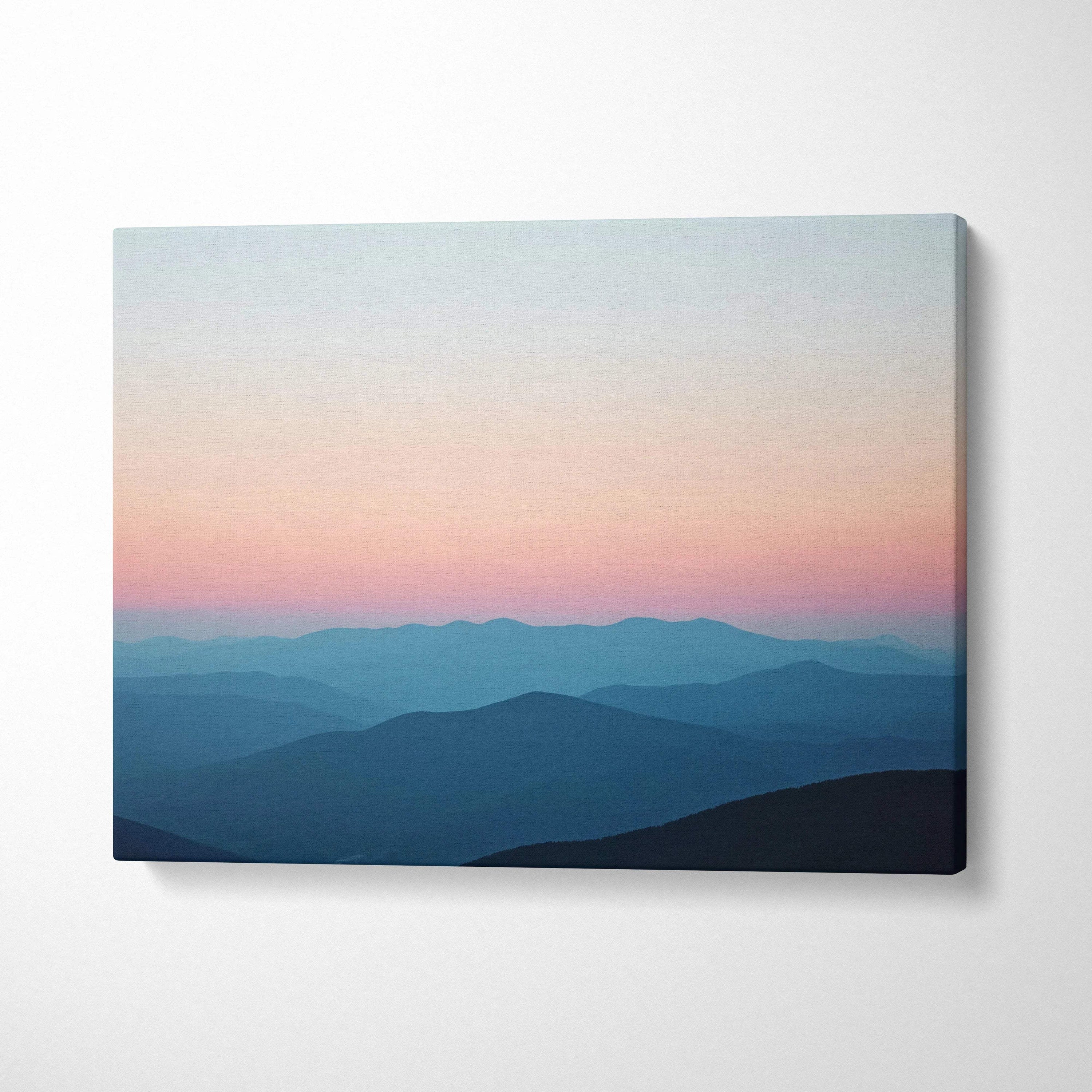 Canvas print of serene sunrise over mountains in calm pastel sky blues and pink