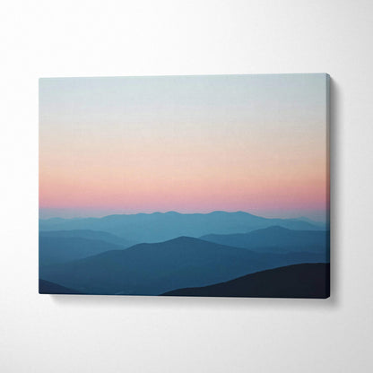 Canvas print of serene sunrise over mountains in calm pastel sky blues and pink
