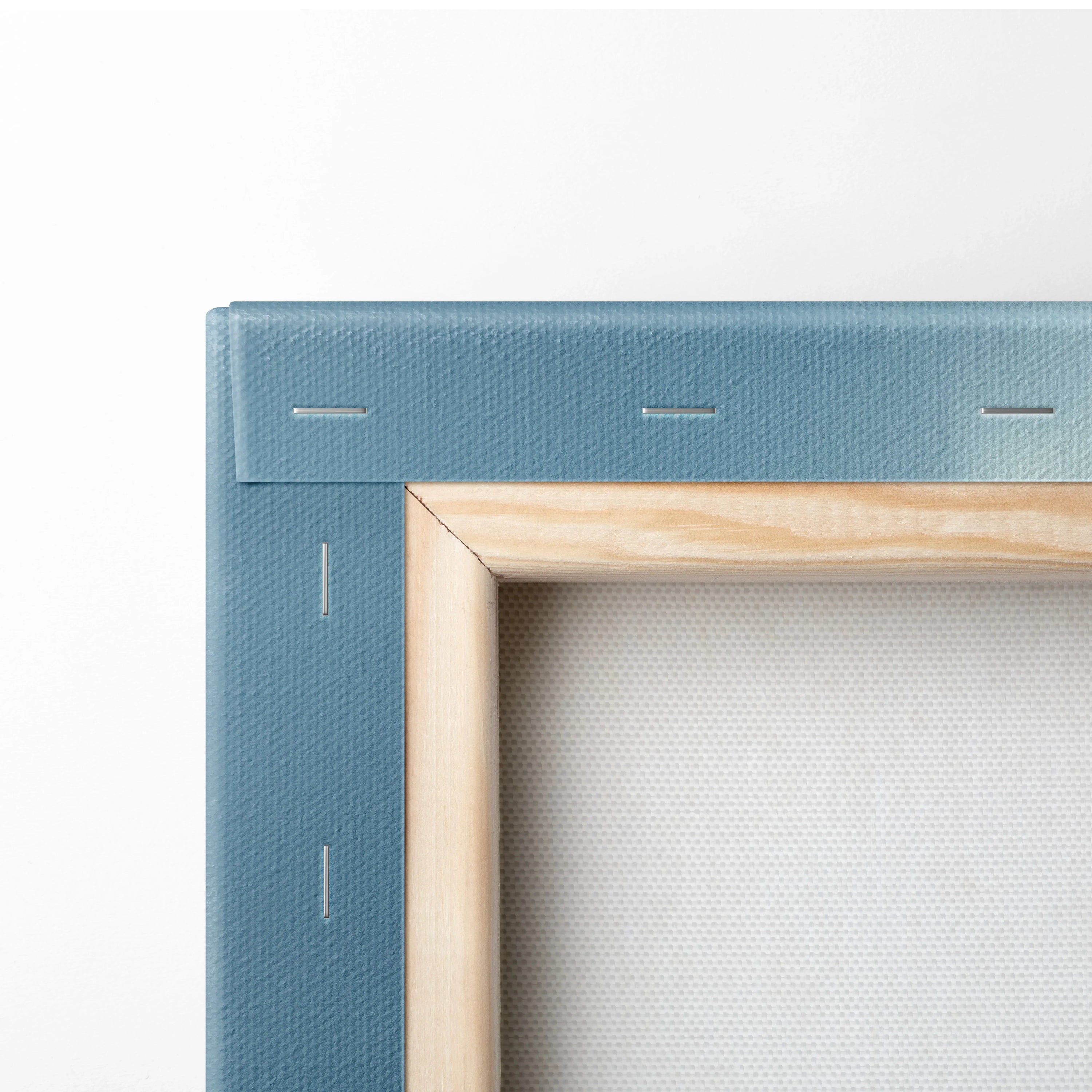 Close-up of blue-stretched canvas with natural wood frame showing staples and textured fabric for wall art.