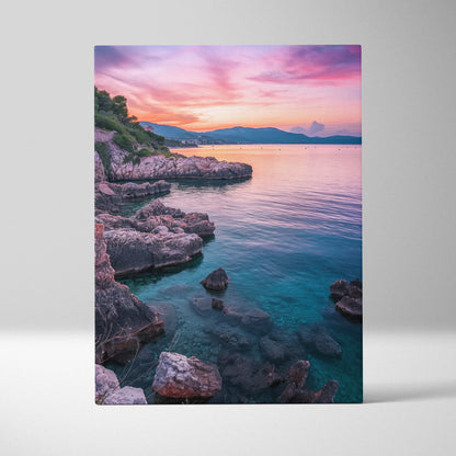 Canvas wall art featuring a rocky beach at sunset with pink and purple sky over calm blue water.