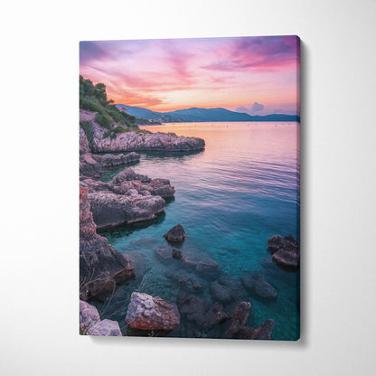 Canvas wall art featuring a vibrant beach sunset with pink, purple, and orange sky over rocky shoreline and calm blue water.
