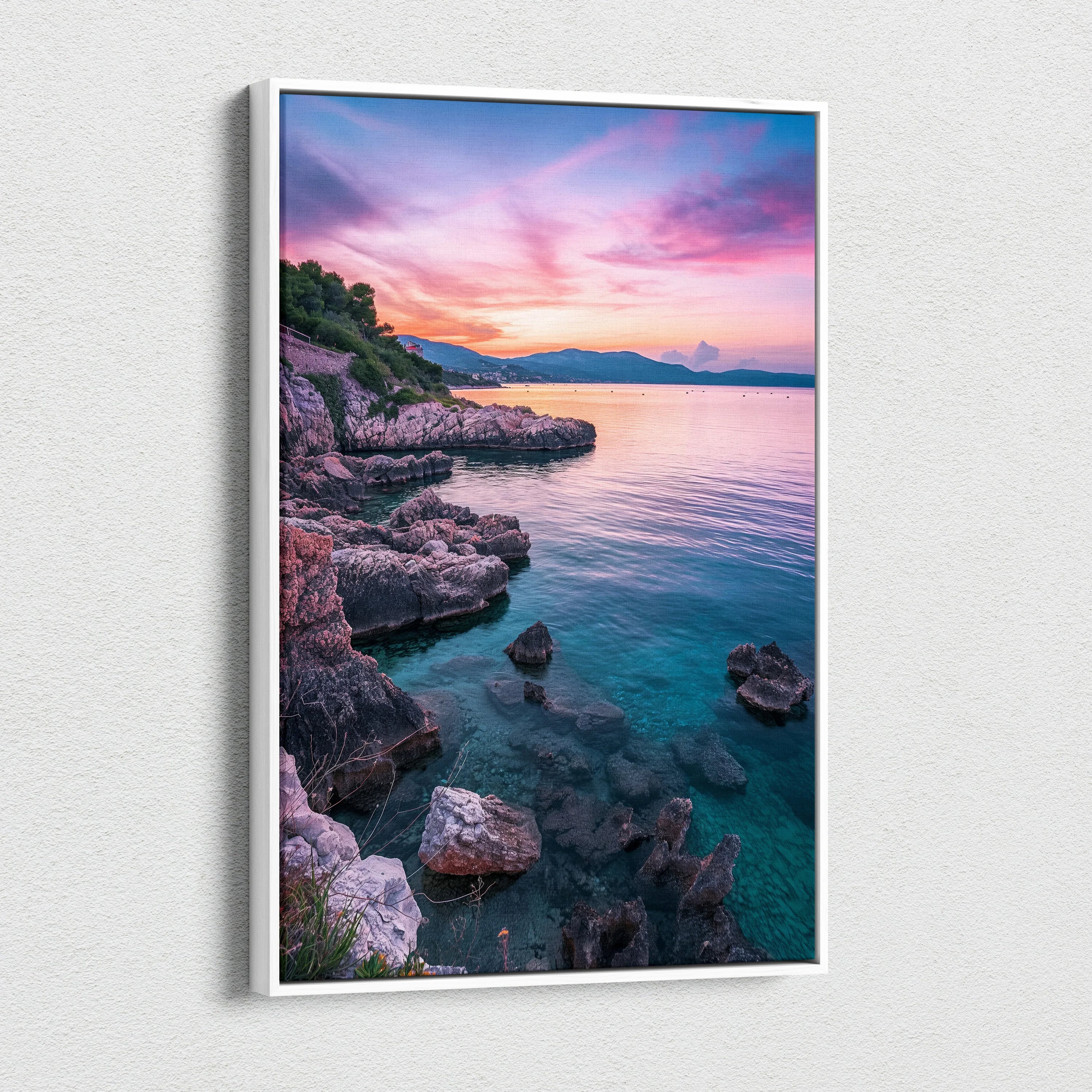 Canvas wall art depicting a rocky beach at sunset with vibrant pink and purple sky over calm blue water.