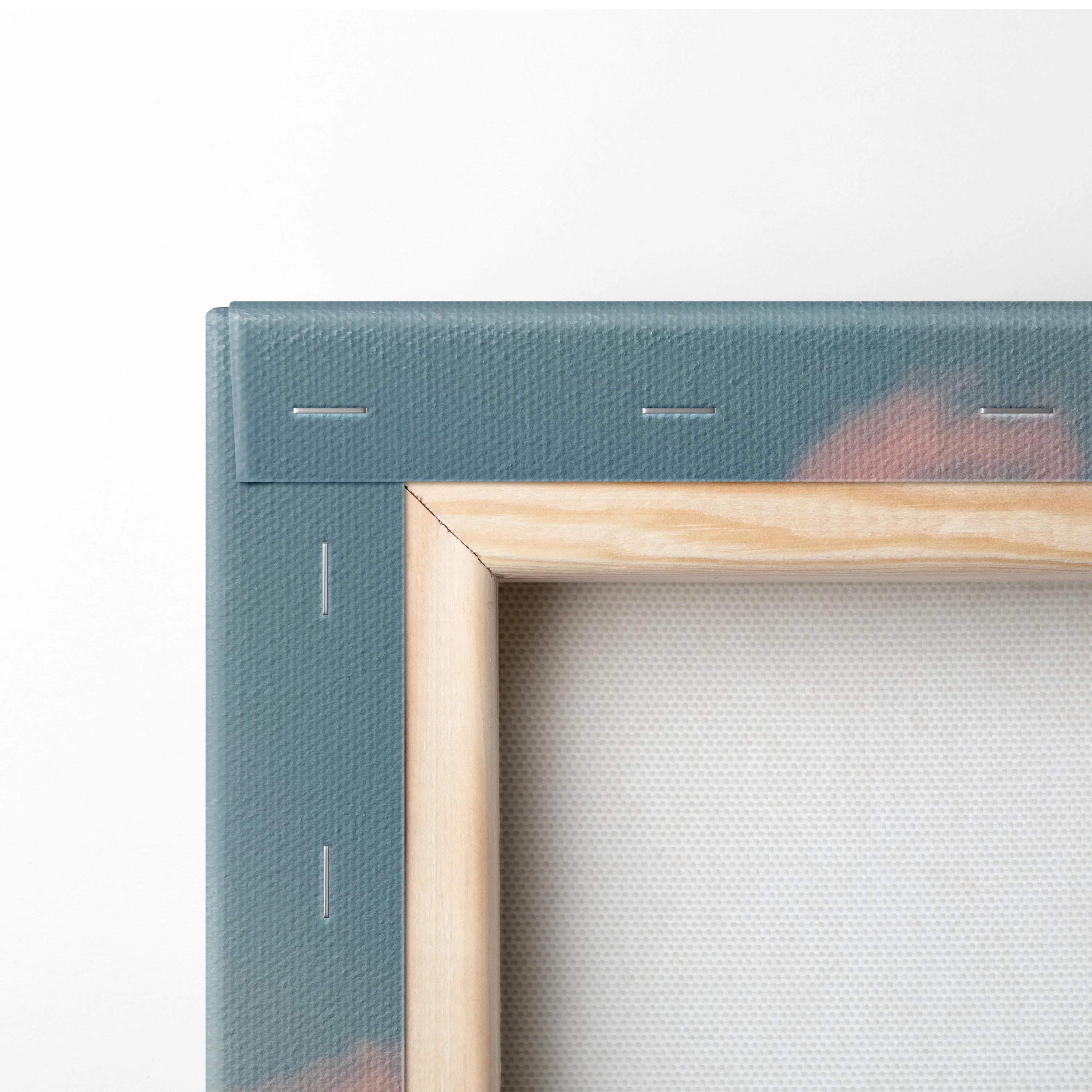 Close-up of stretched canvas corner with wooden frame and teal backing showing staples and fabric texture.