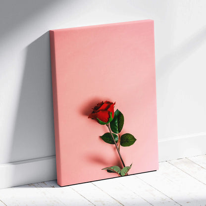 Vibrant red rose on pastel pink canvas wall art with green leaves
