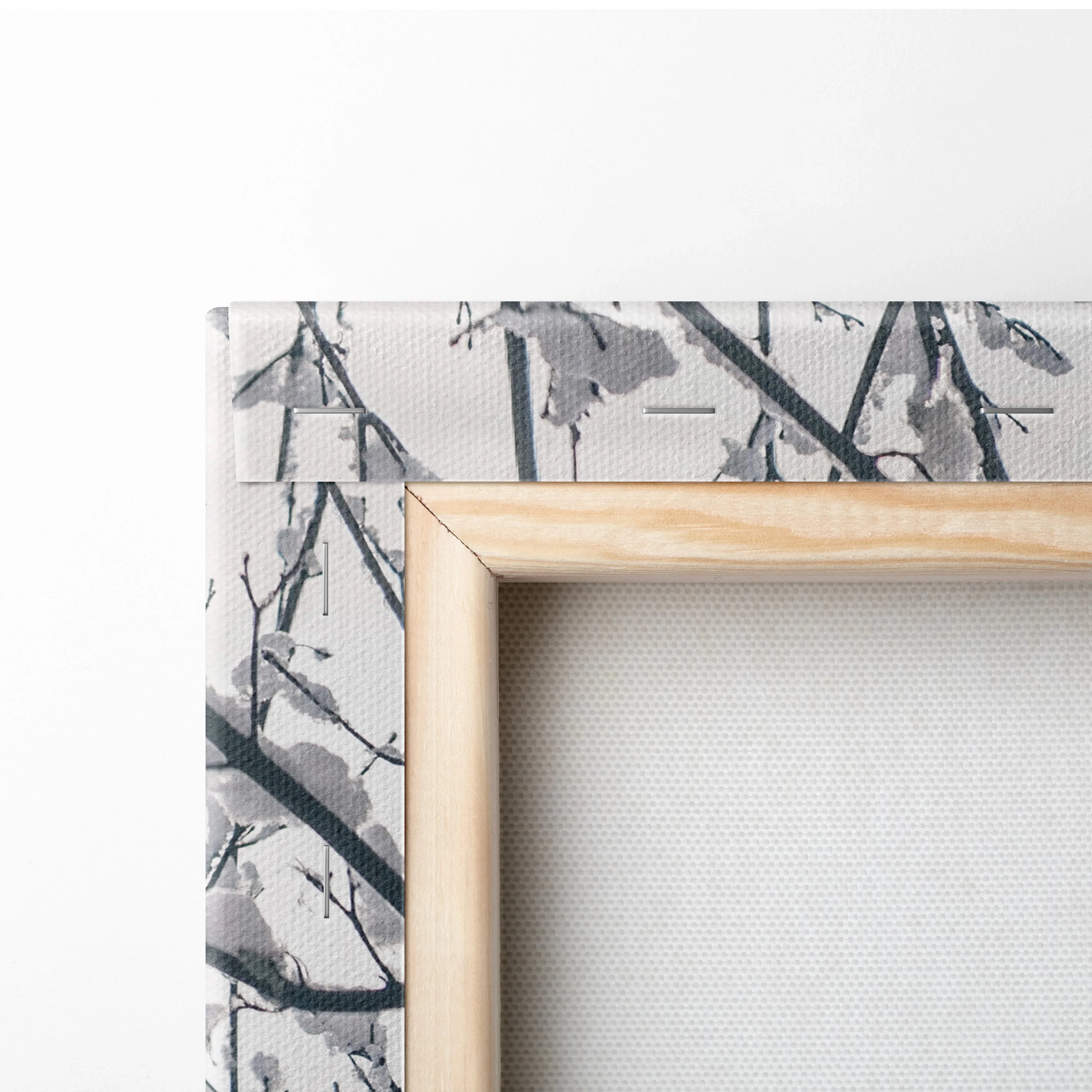 Close-up of canvas wall art corner with wooden frame and digital print of snowy branches in grayscale tones.