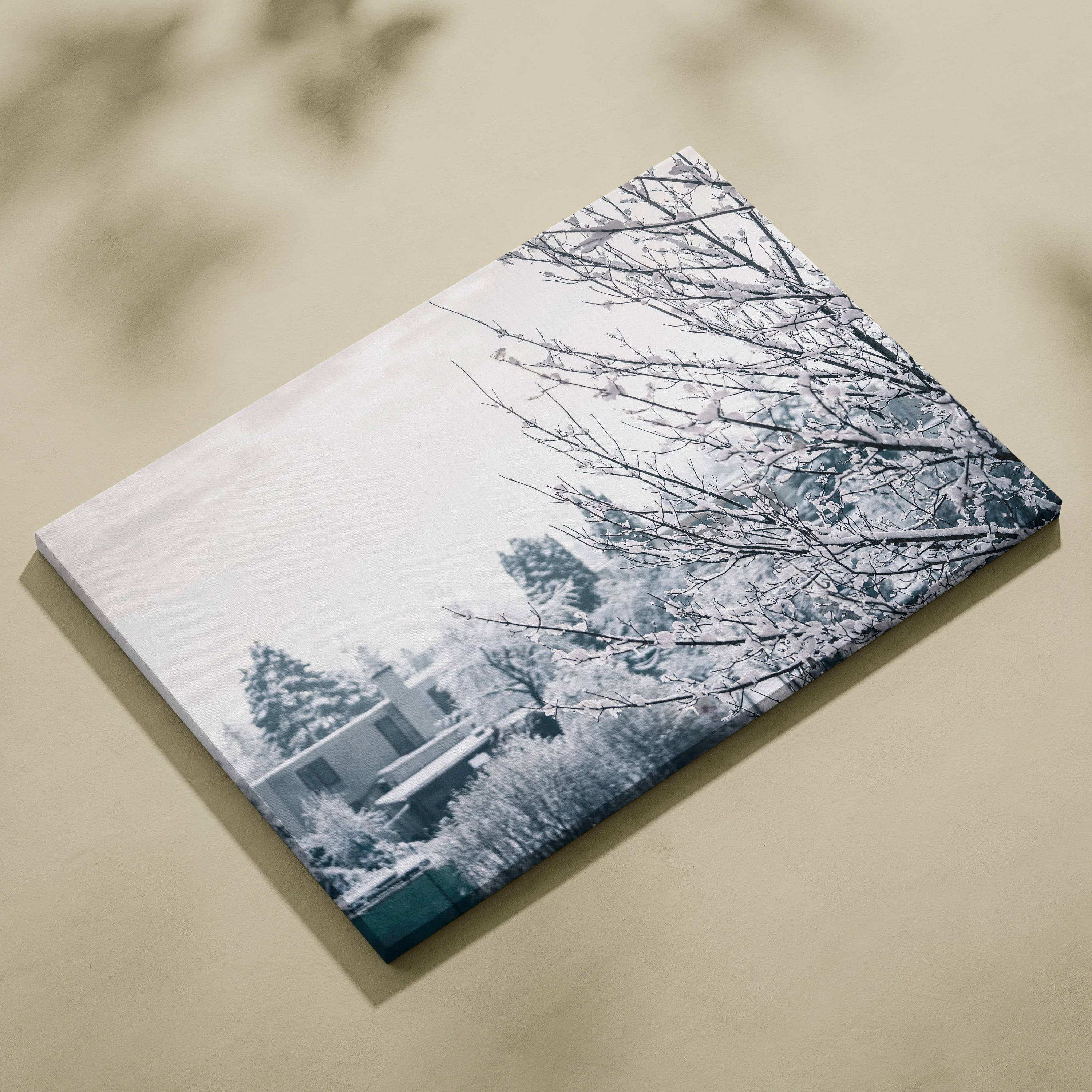 Canvas wall art featuring a serene winter scene with snow-covered branches and trees in soft blue and white tones.