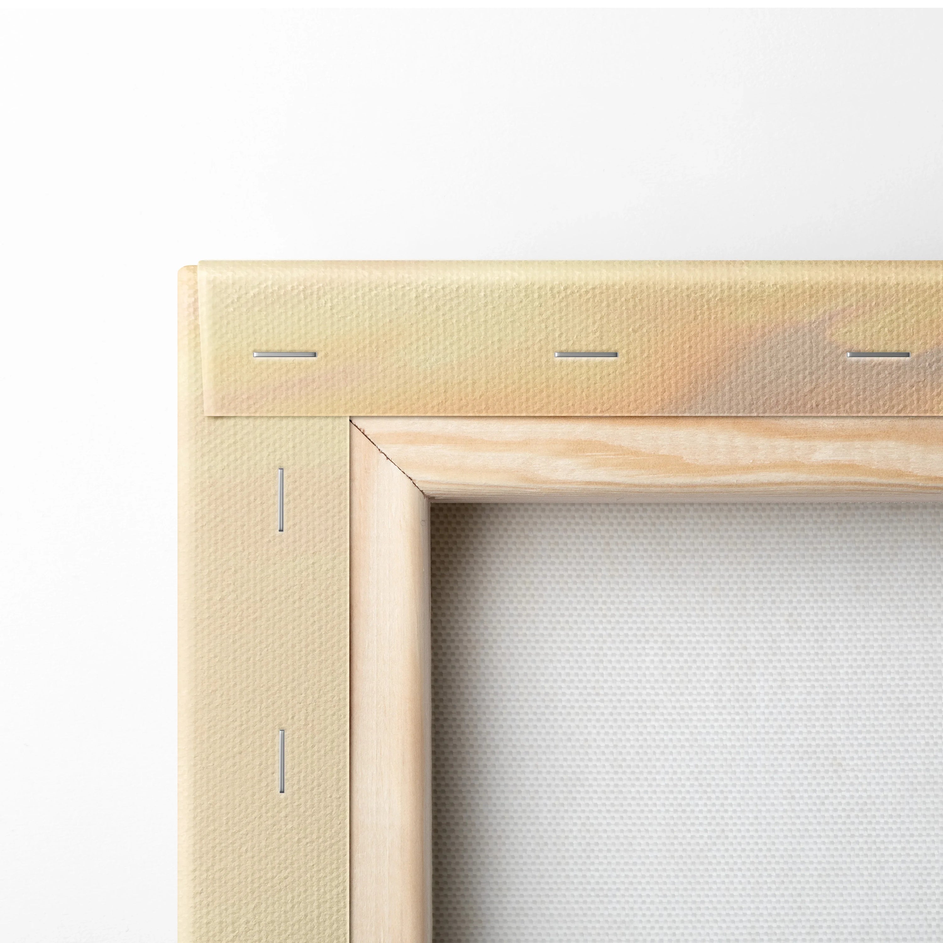 Close-up of wooden frame corner with stretched white canvas and visible metal staples for wall art decor.