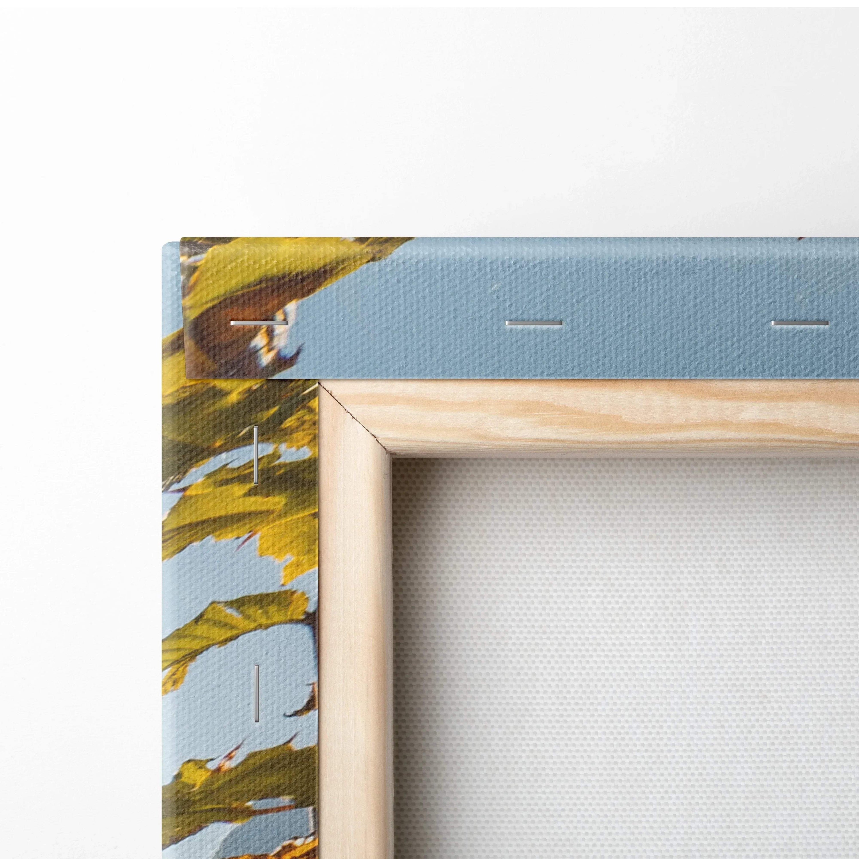 Close-up of canvas wall art corner with blue background, yellow floral design, and wooden stretcher frame.