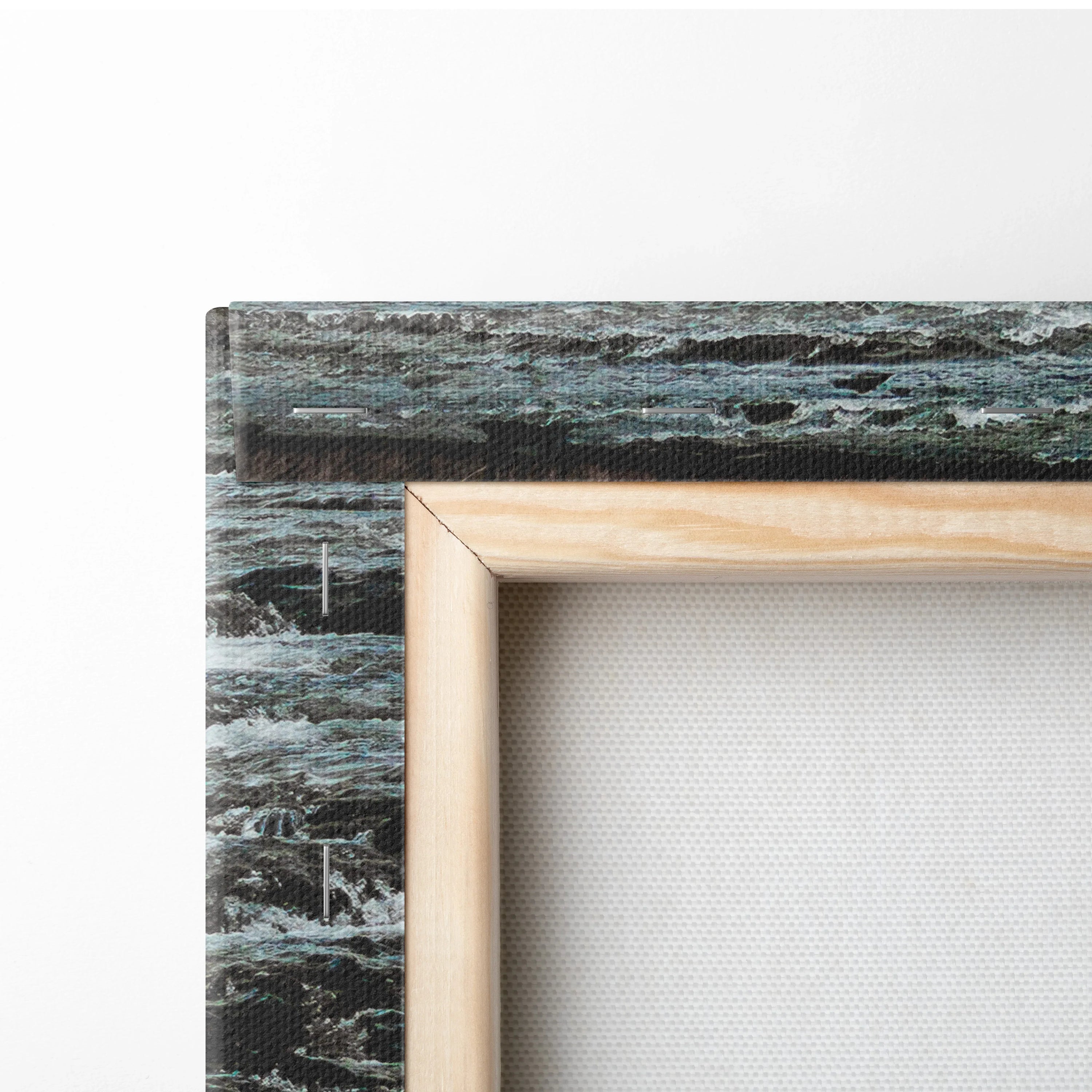 Close-up of wrapped canvas with natural wood frame showing textured fabric and blue-gray waterfall print on side for wall.
