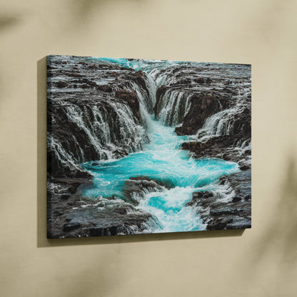Canvas wall art featuring a turquoise waterfall flowing through rugged gray rocks for nature decor.