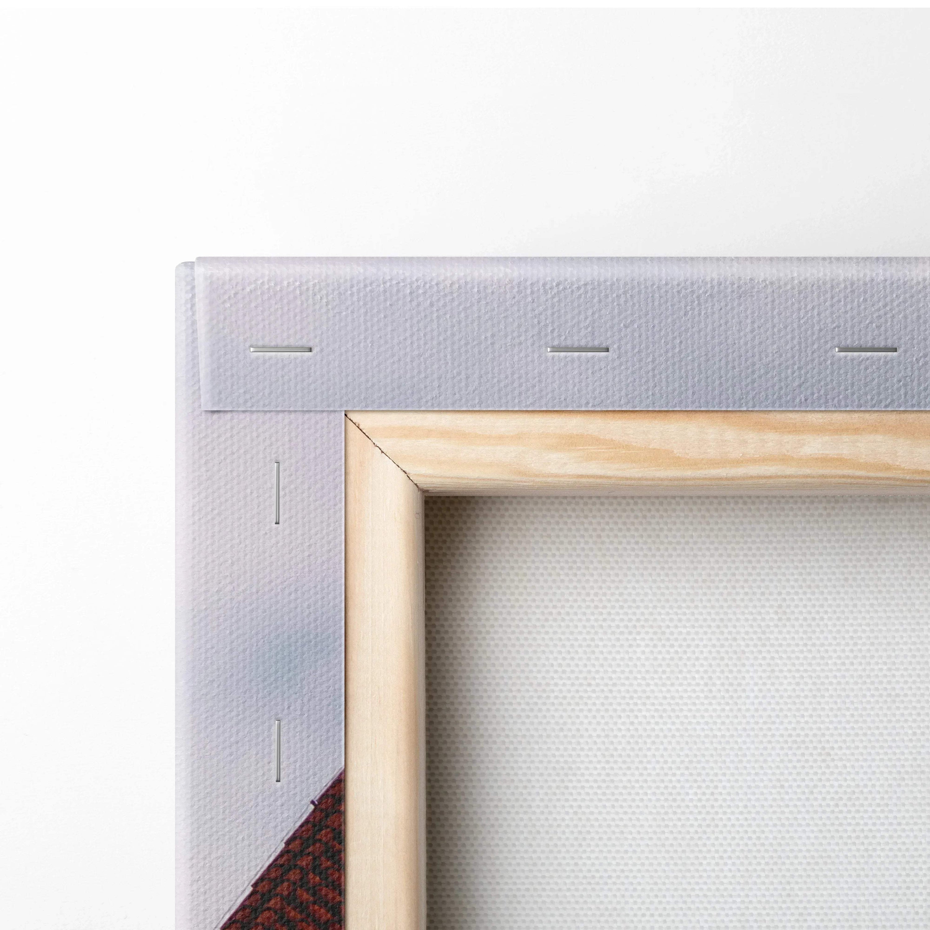 Close-up of light wood frame and stretched white canvas fabric with visible staples for wall art print.