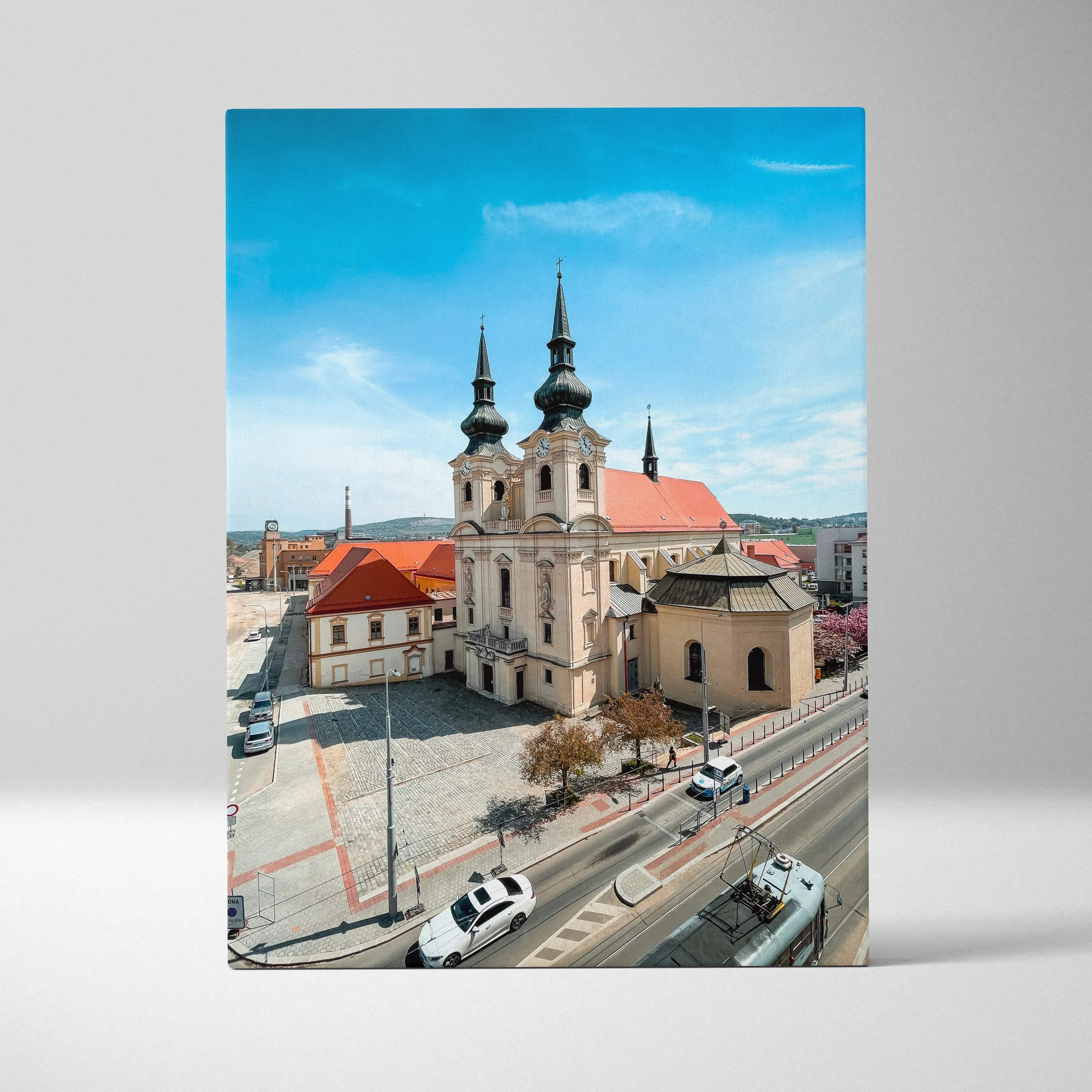 A rectangular canvas print of a vibrant aerial view of a historic church with twin spires under a bright blue sky