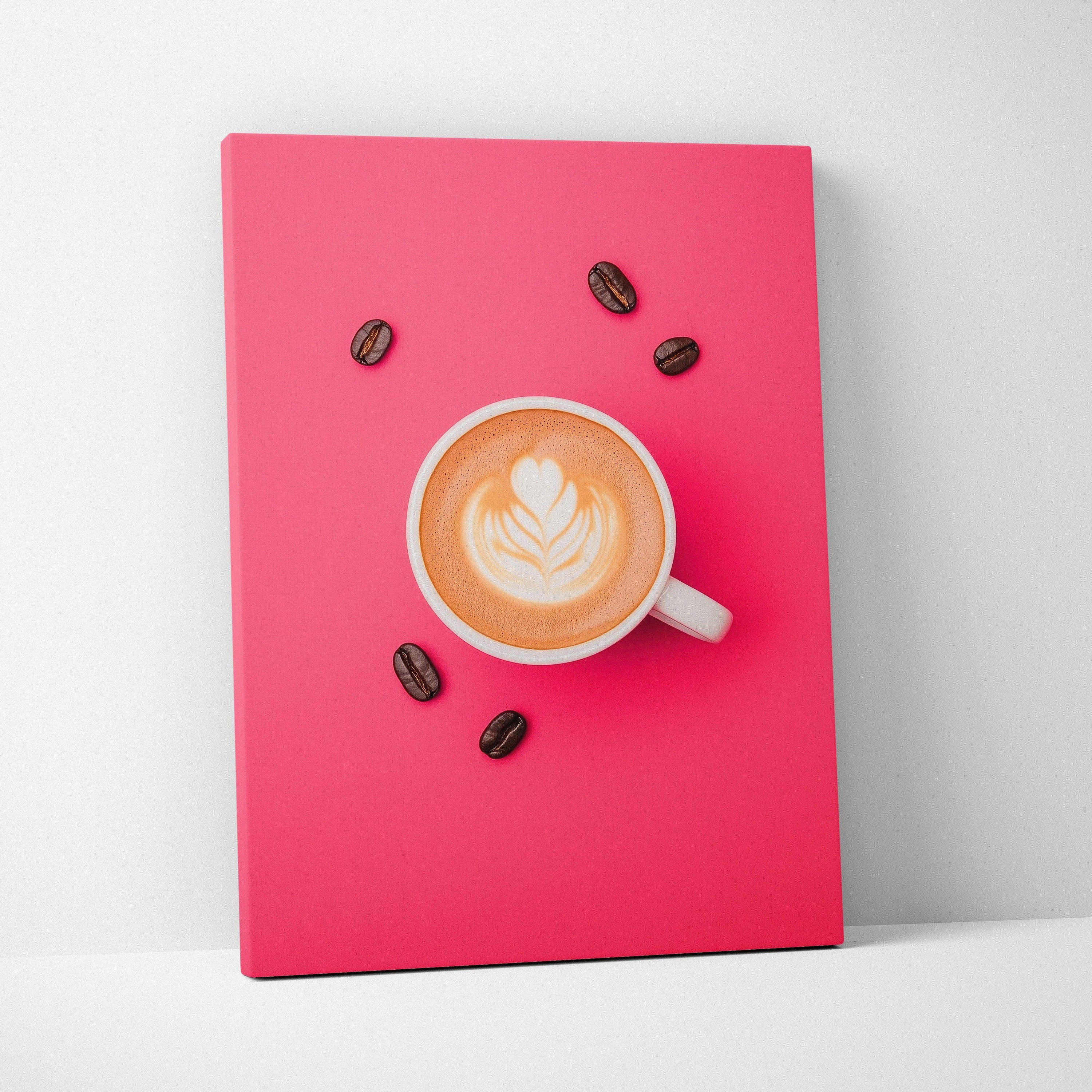 Canvas wall art featuring a white coffee cup with latte art and scattered coffee beans on a vibrant pink background.