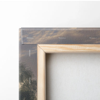 Close-up of wooden-framed canvas wall art featuring forest and mountain sunset scene with rich, warm tones.