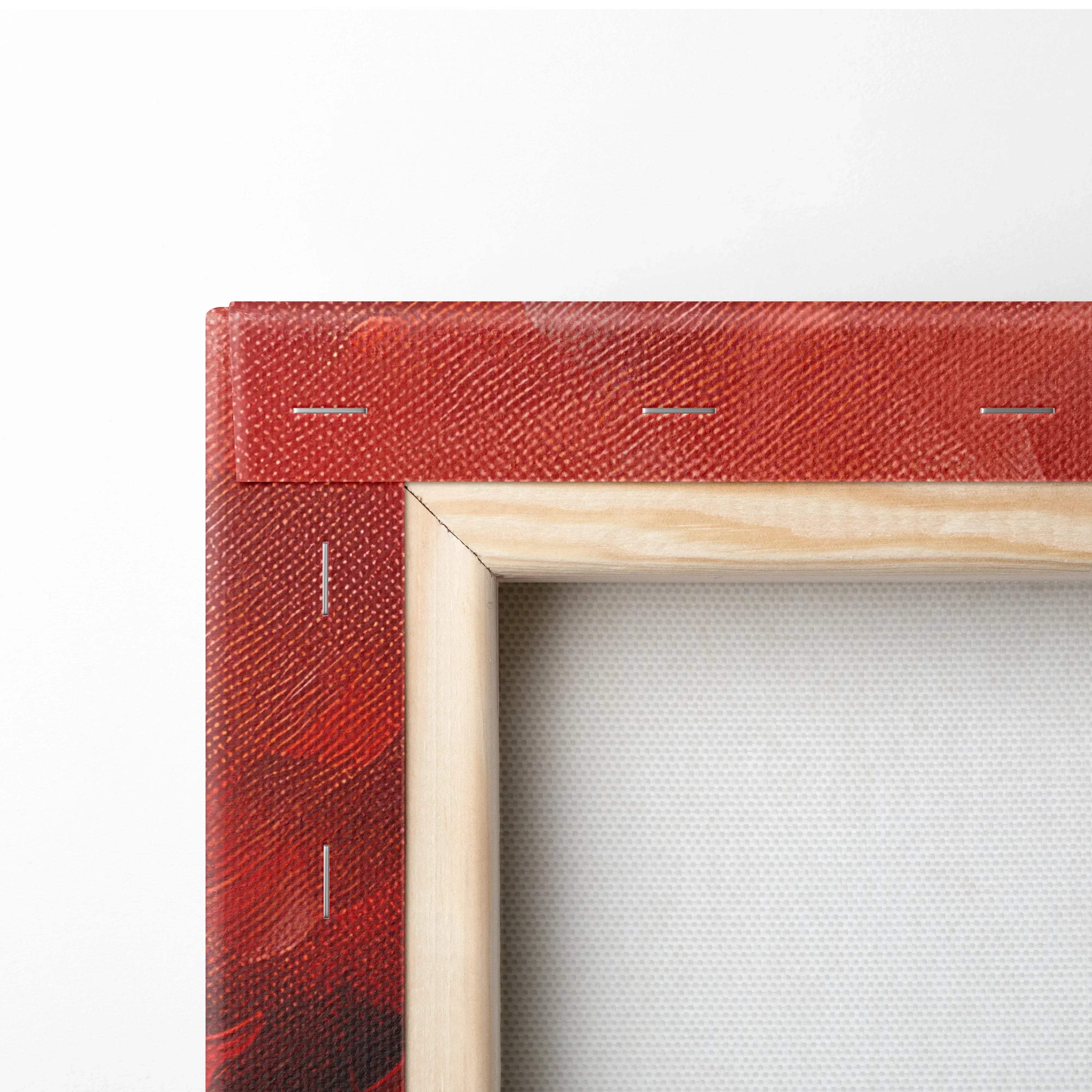 Close-up of corner on red textured canvas art stretched over wooden frame with visible staples and natural wood edges.