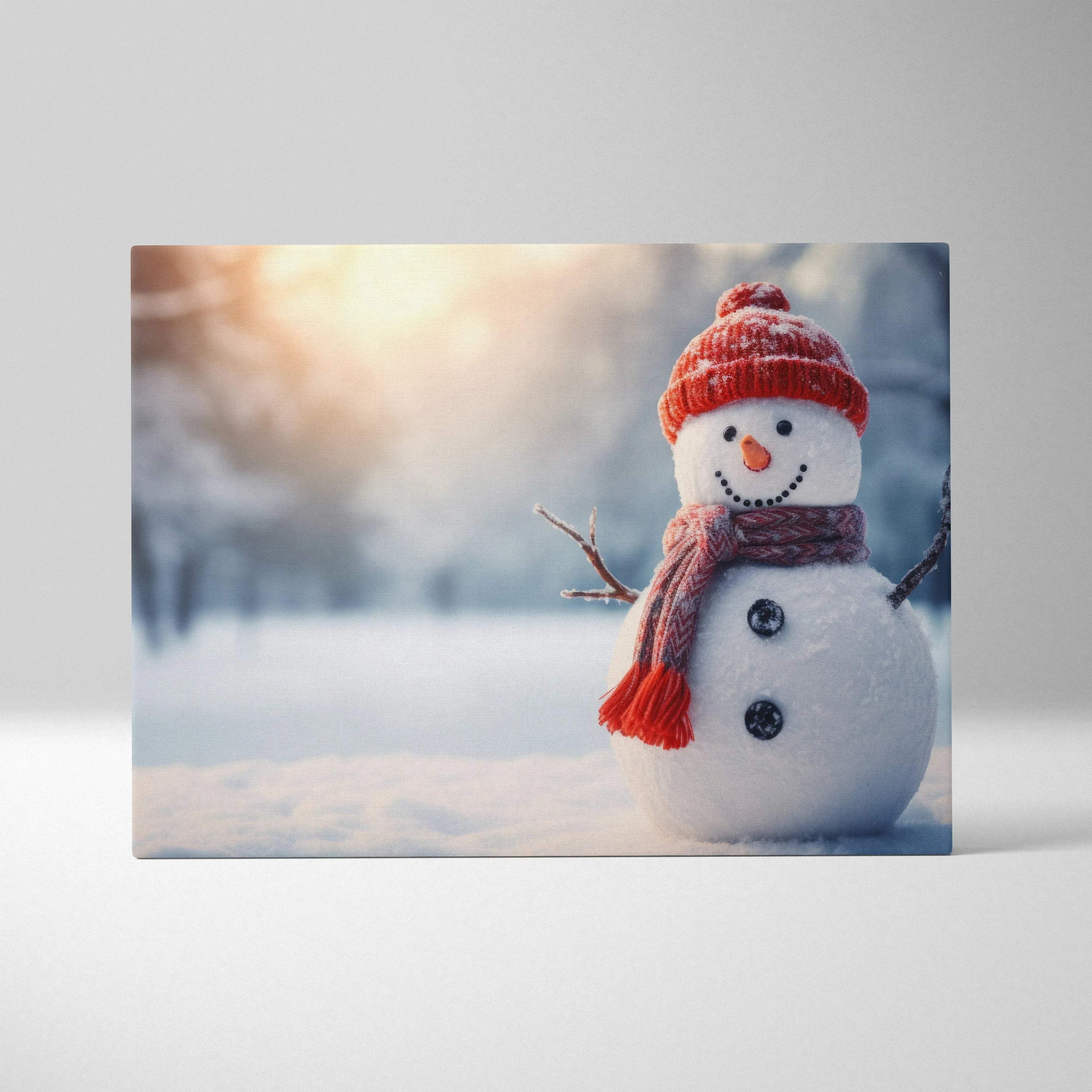 Canvas wall art featuring a cheerful snowman with a red knit hat and scarf in a snowy landscape with soft sunlight.