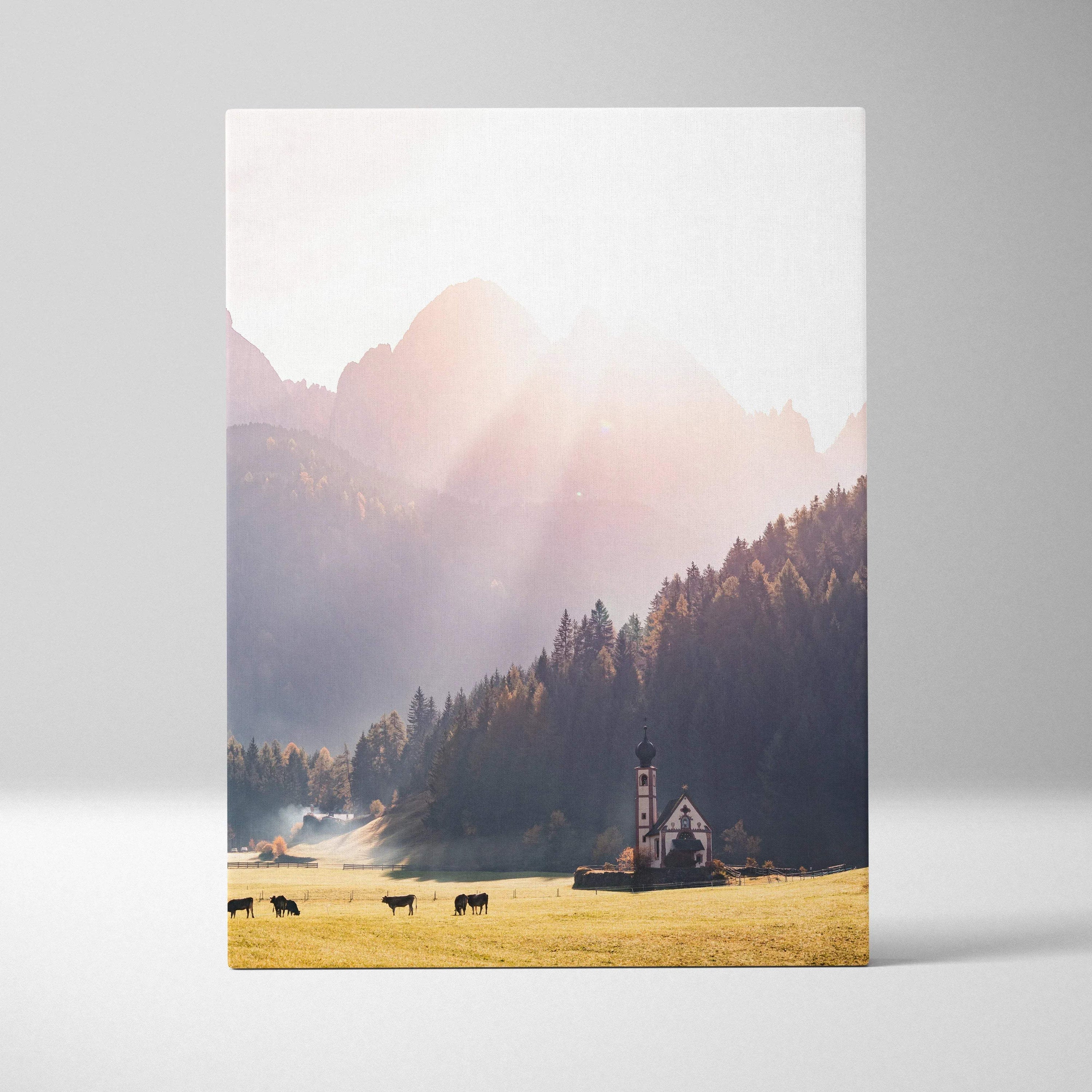 Vertical canvas wall art featuring a sunlit autumn mountain landscape with grazing cows and a charming church.