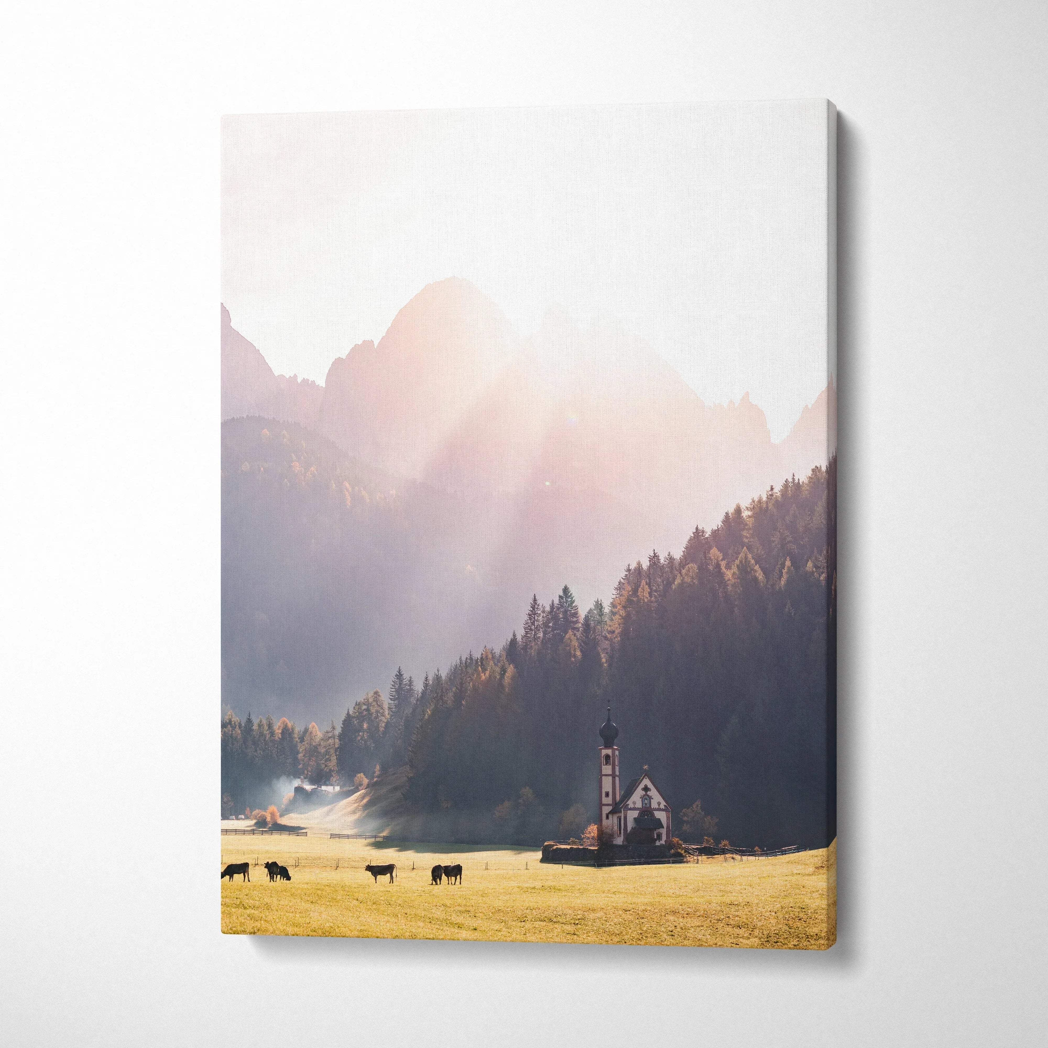 Vertical canvas wall art featuring autumnal mountains, sunlit trees, and a small church in a golden field.