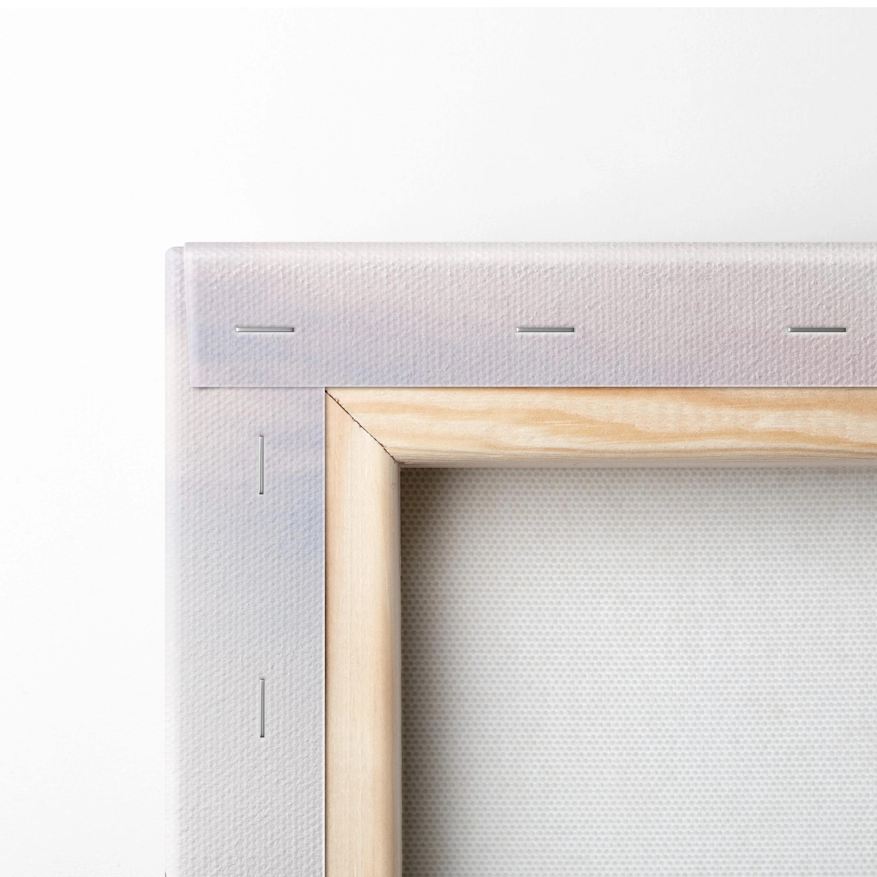Close-up of canvas stretched over wooden frame with visible staples securing fabric.