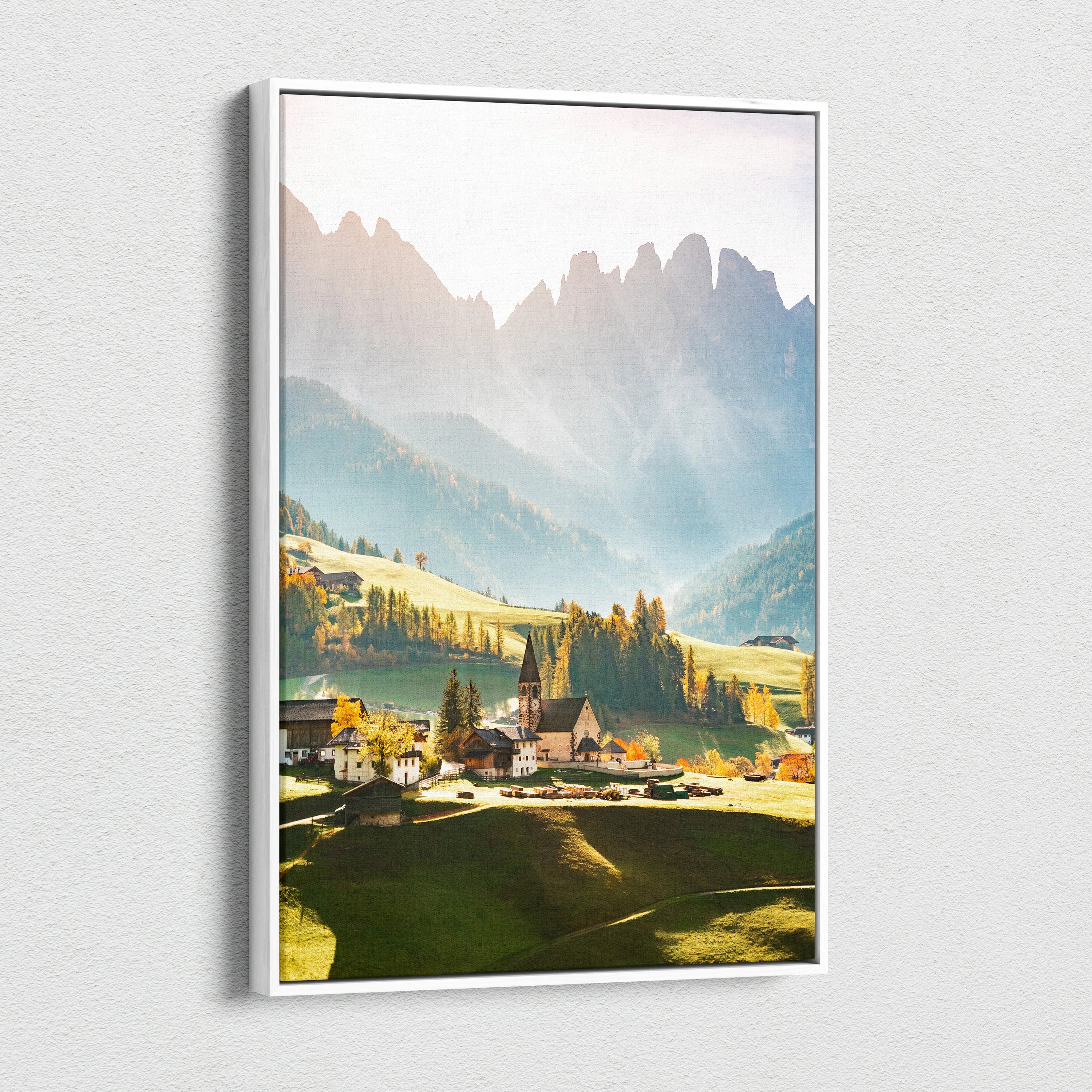 Vertical canvas wall art featuring a sunlit mountain village with sharp peaks and warm golden tones.