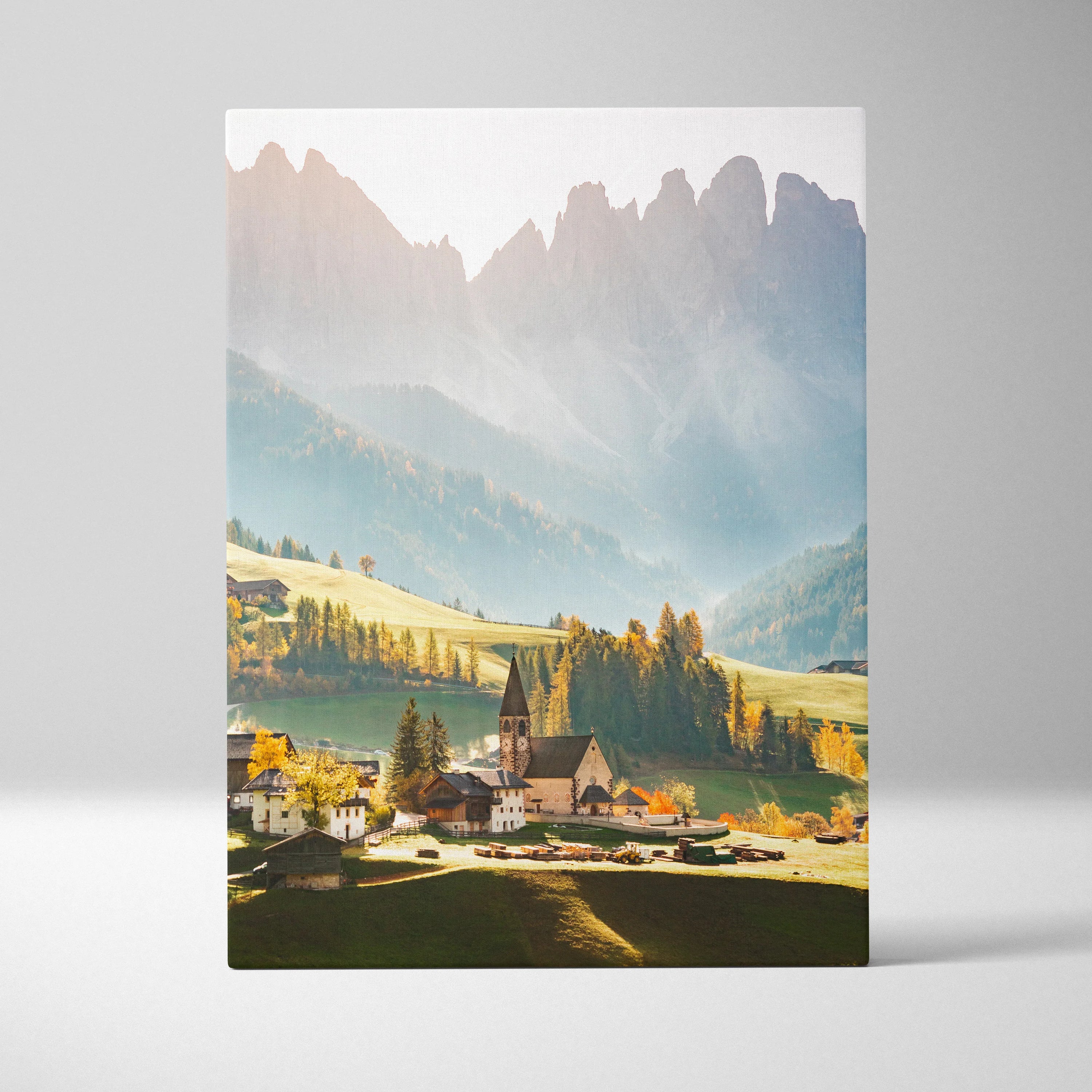 Vertical canvas wall art featuring sunlit mountain village and towering peaks in soft morning light.
