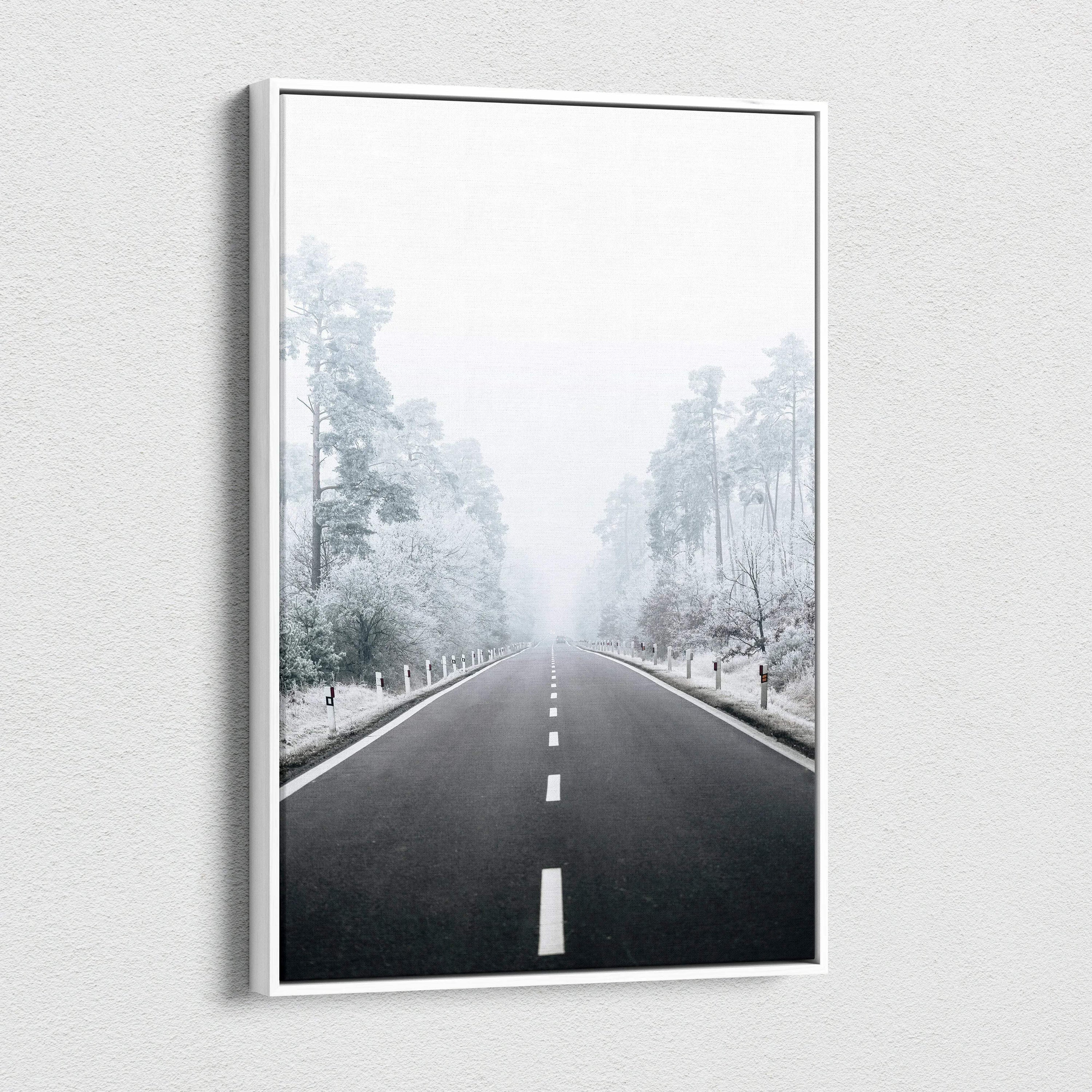 Canvas wall art depicting a snowy road flanked by frost-covered trees in a misty winter landscape.
