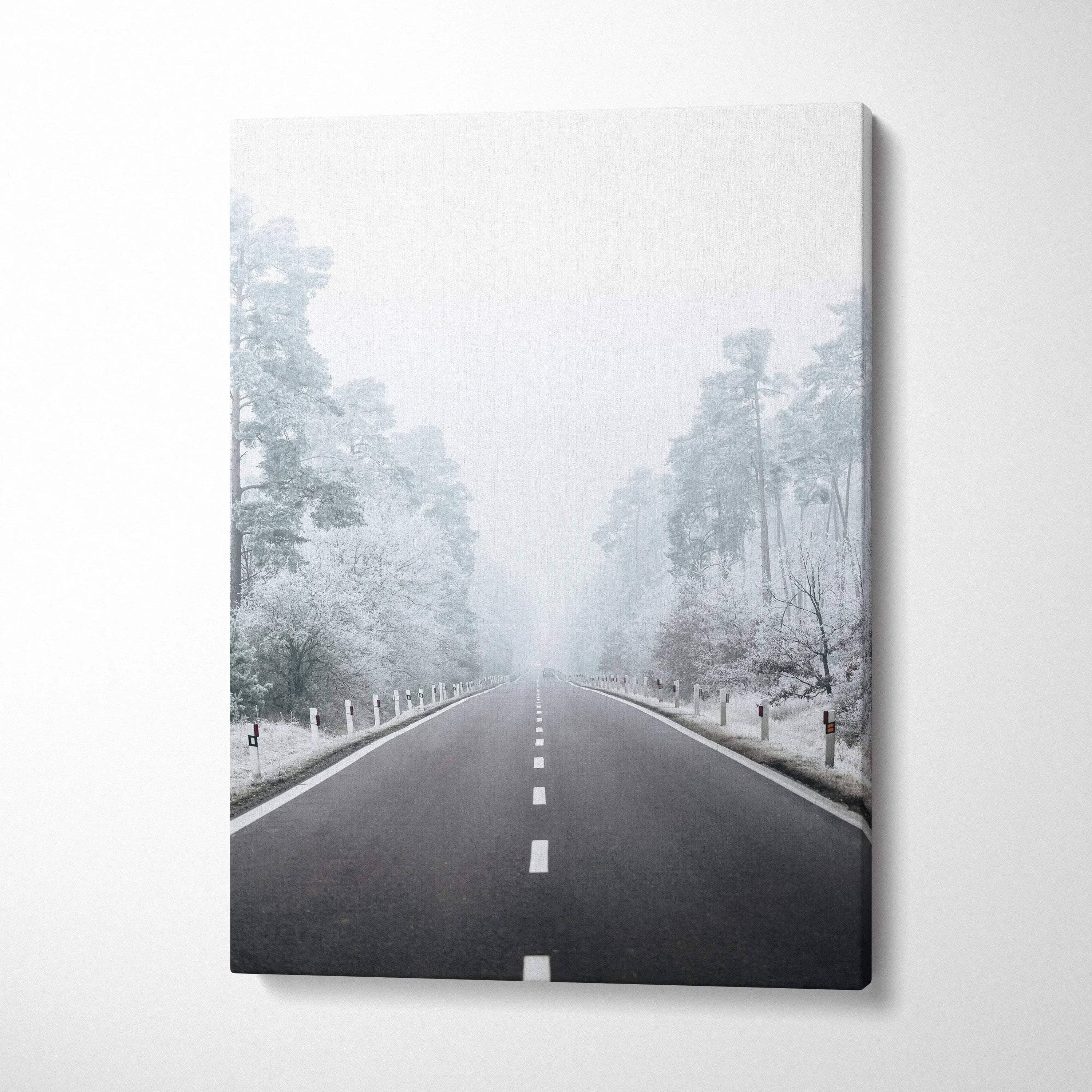 Vertical canvas wall art featuring a snowy road flanked by frosted trees in a serene winter landscape decor piece.