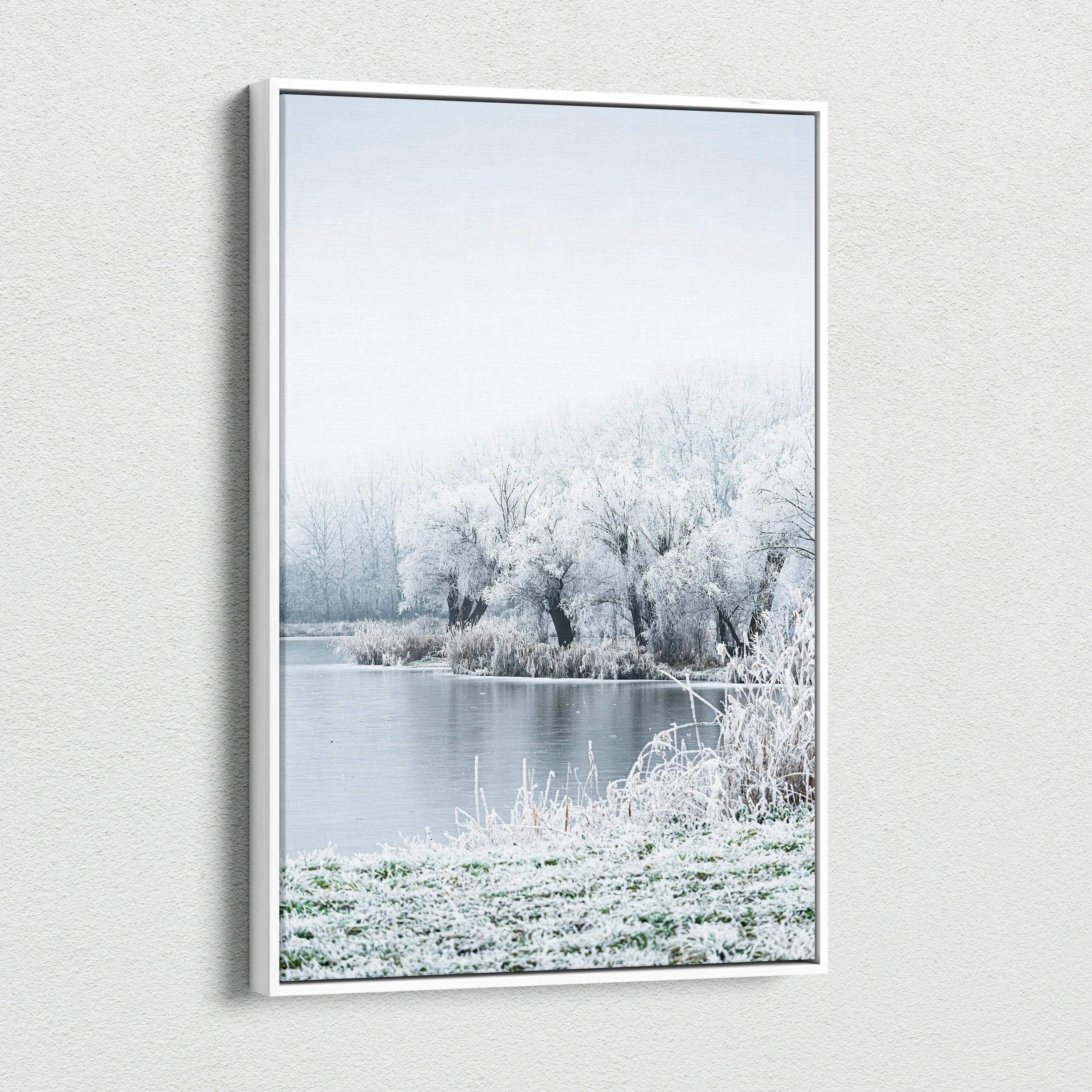 Canvas wall art featuring a serene snowy landscape with frost-covered trees and a calm river under a pale sky.