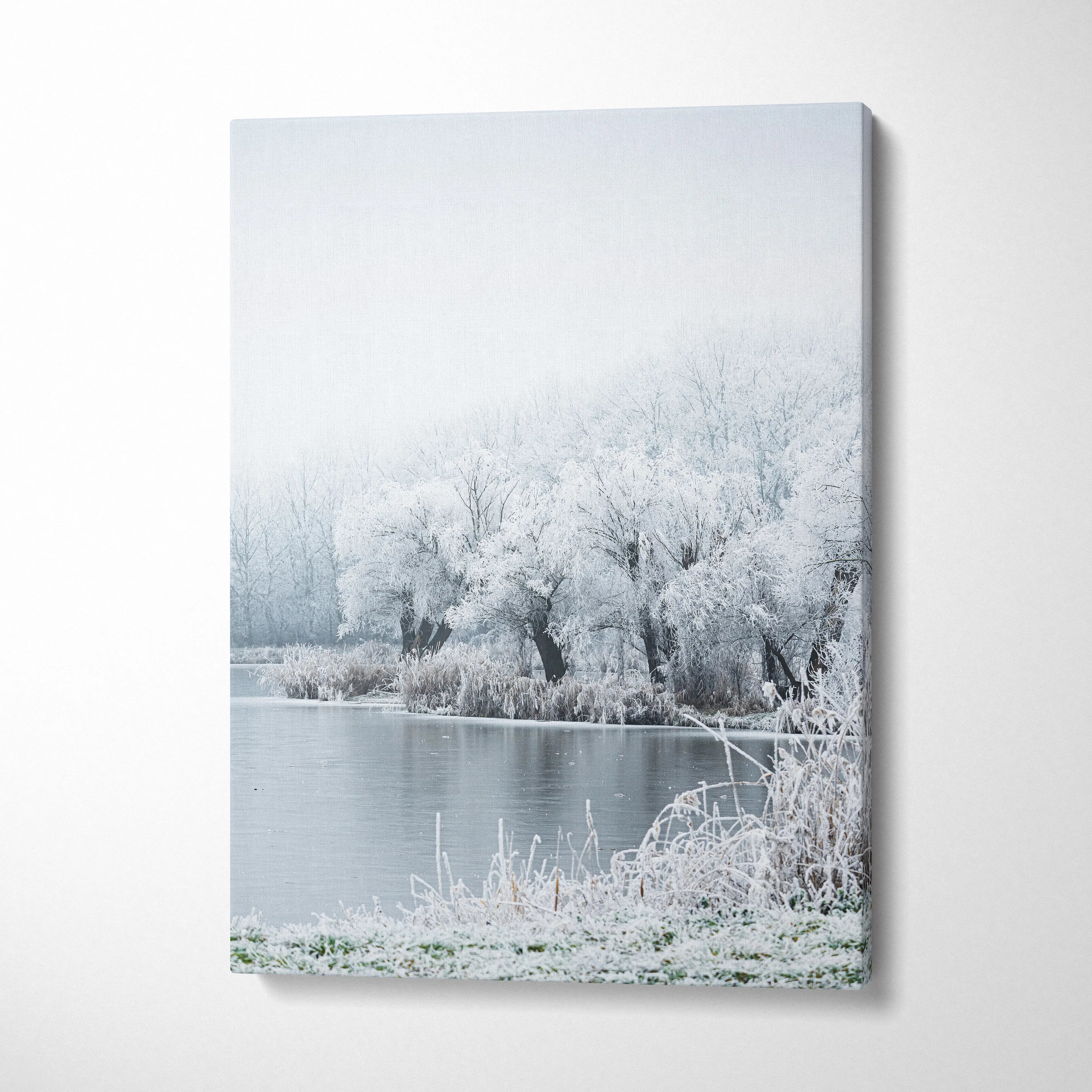Winter landscape canvas wall art featuring snow-covered trees and a icy pond in soft muted tones.