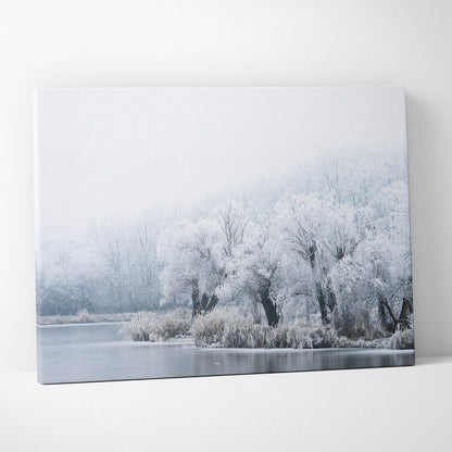 Canvas wall art depicting snow-covered trees with frosty branches by a calm, icy lake under a pale, misty sky.