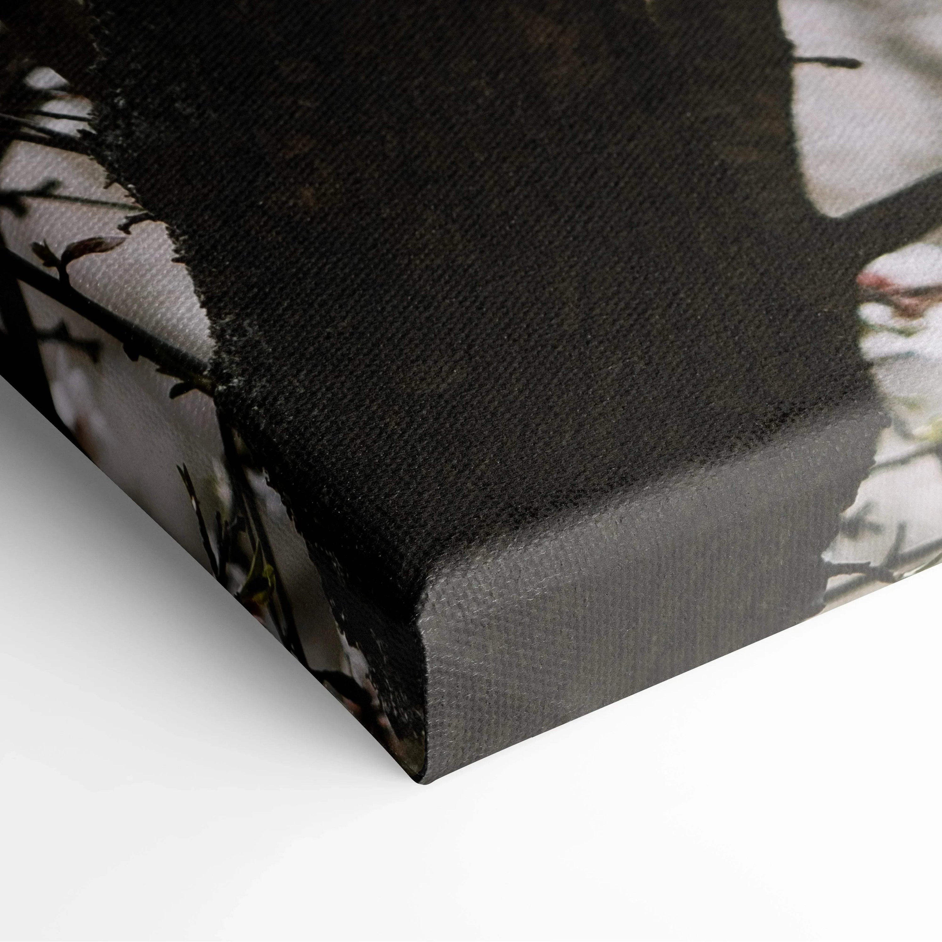 Close-up of black-framed canvas wall art corner with cherry blossom floral decor texture.