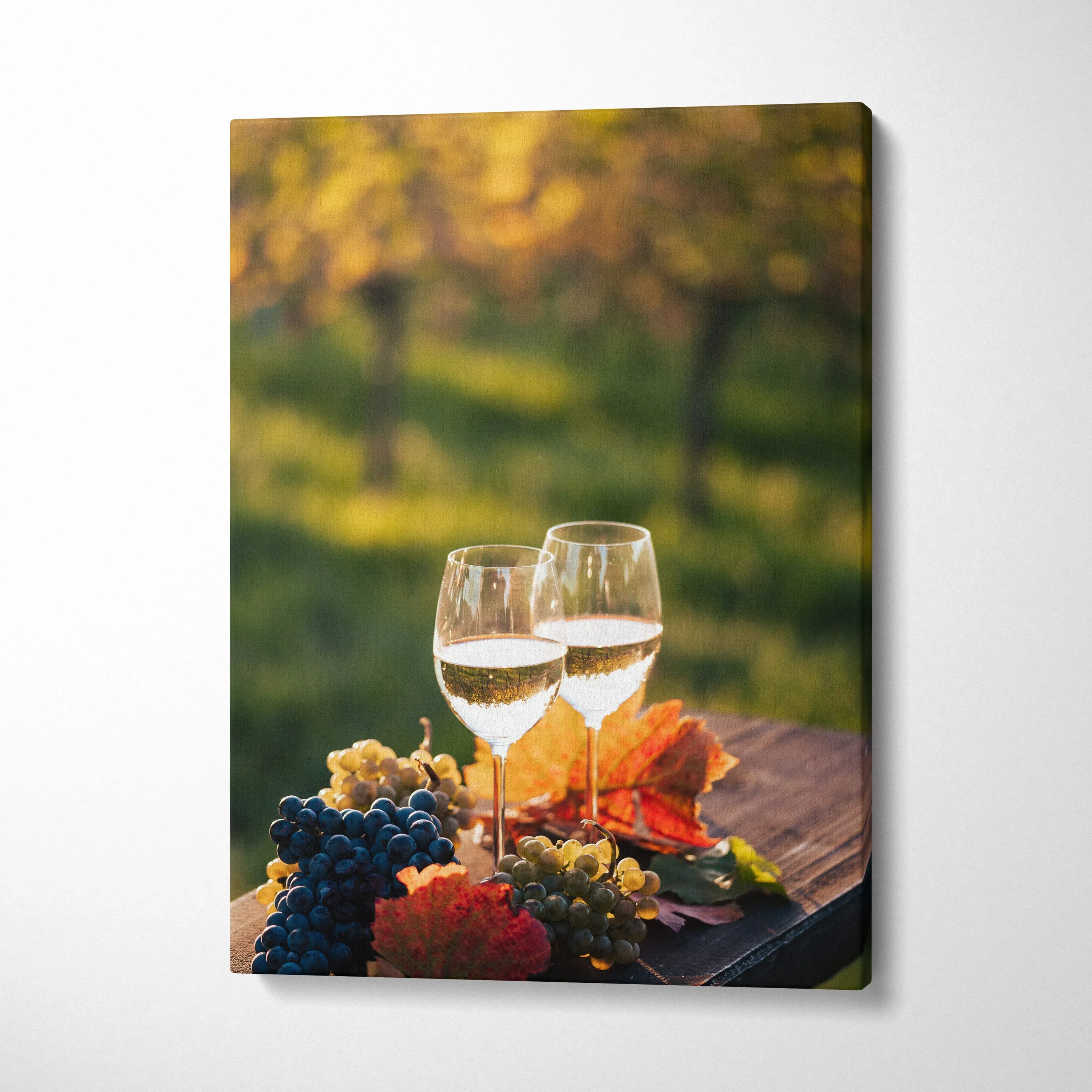 Canvas wall art featuring two wine glasses with grapes and autumn leaves on wooden table, outdoor decor.