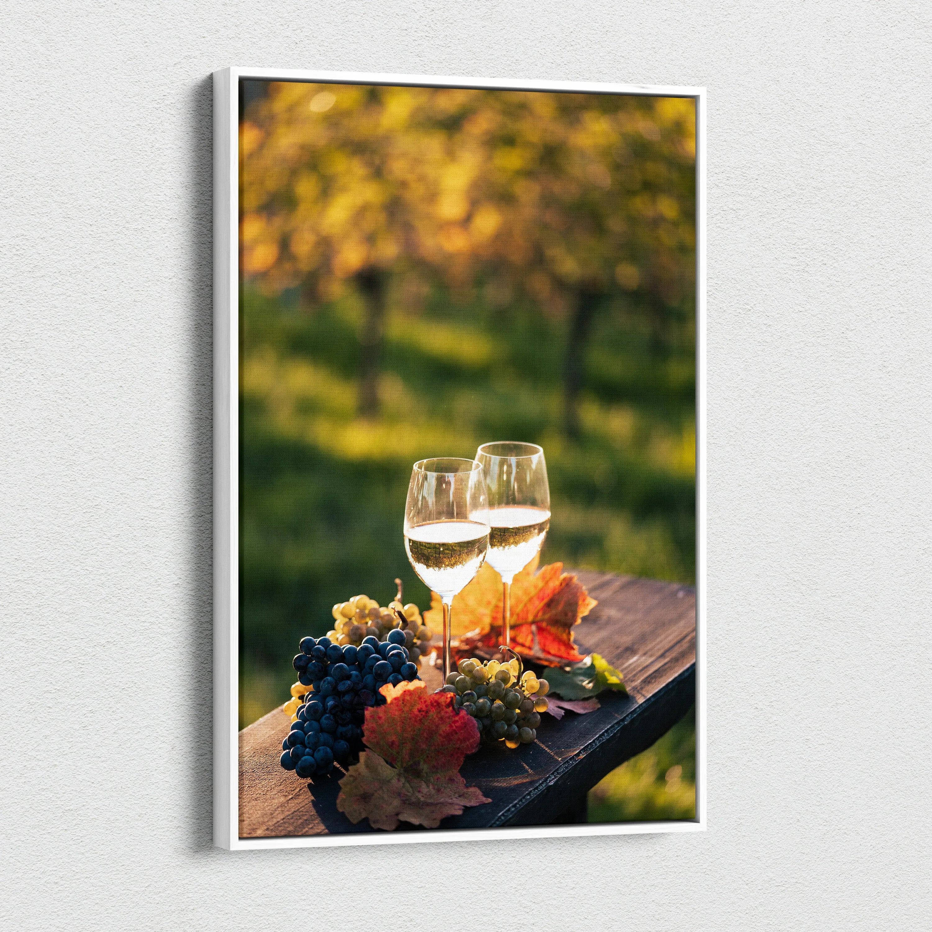 Canvas wall art featuring two wine glasses, clusters of grapes, and autumn leaves on a wooden surface with a blurred.