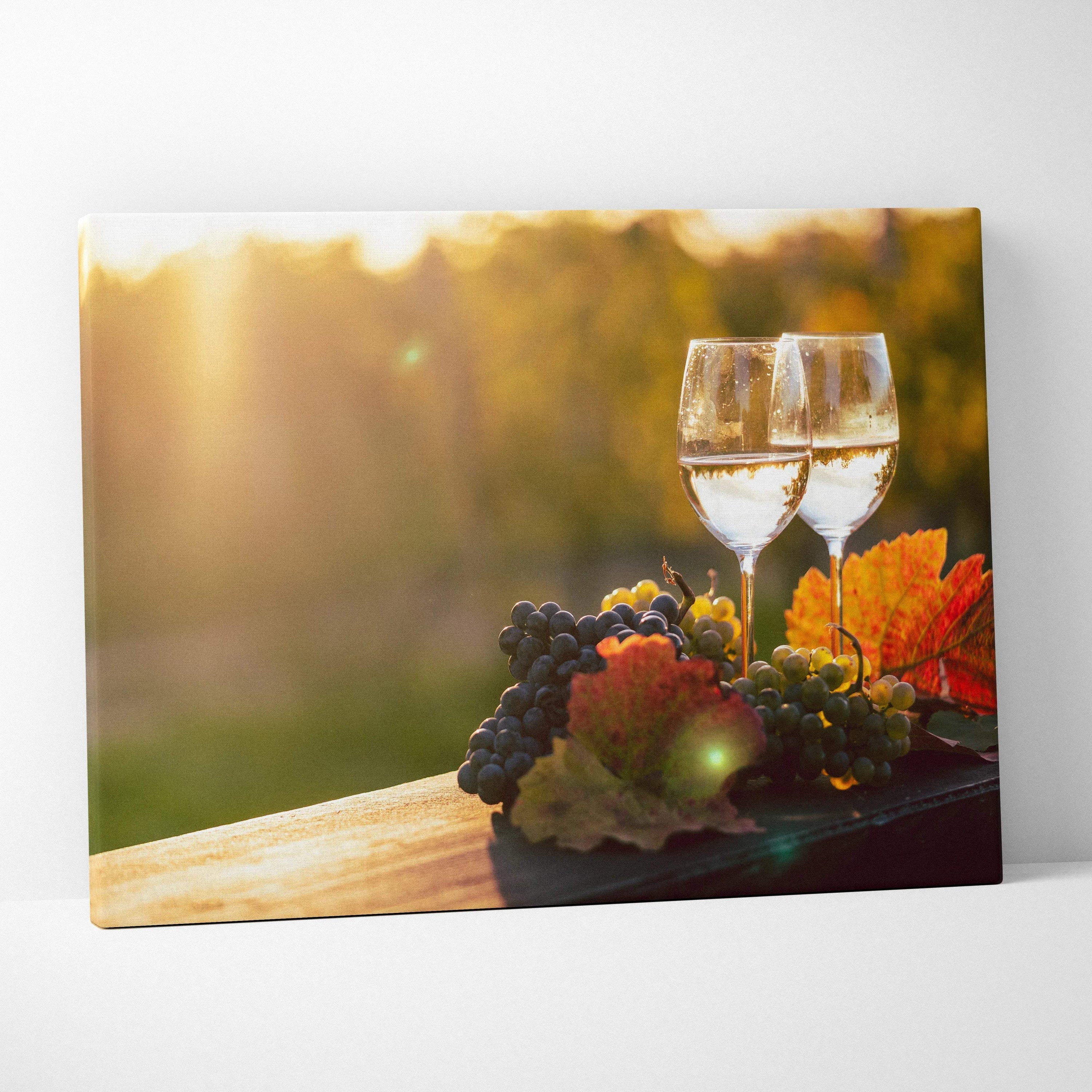 Canvas wall art featuring two wine glasses, grapes, and autumn leaves on wooden surface with warm sunlight background.