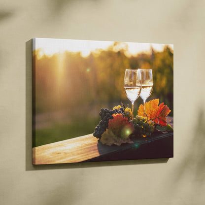 Canvas wall art featuring two wine glasses with grapes and autumn leaves on a wooden surface in warm, golden sunlight.