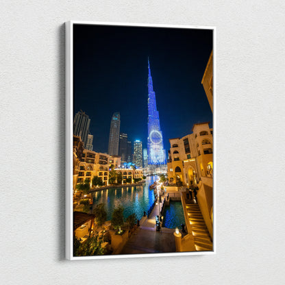 Canvas wall art featuring a nighttime cityscape with illuminated modern skyscrapers and a water canal reflecting vibrant.