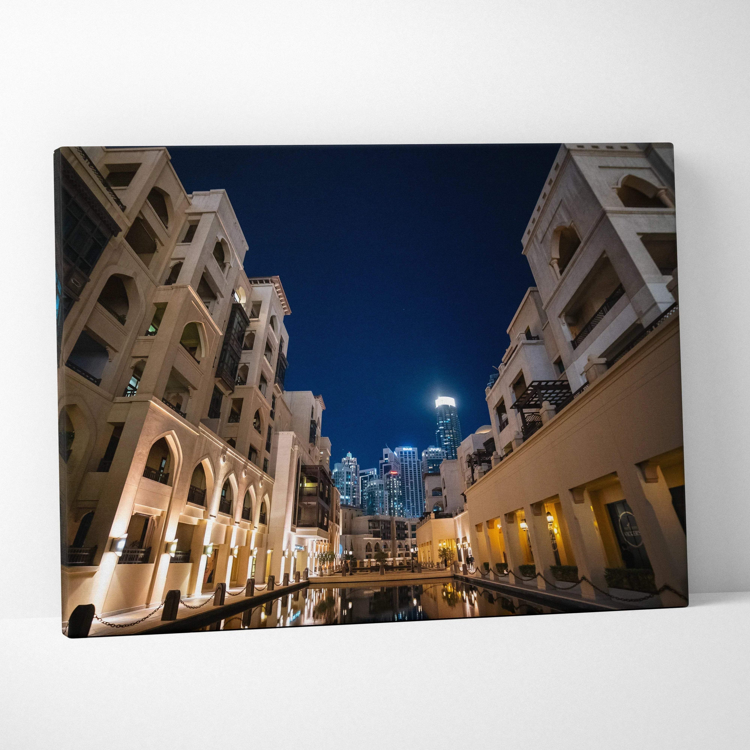 Modern architecture canvas wall art featuring illuminated beige buildings against a deep blue night sky with reflections on.