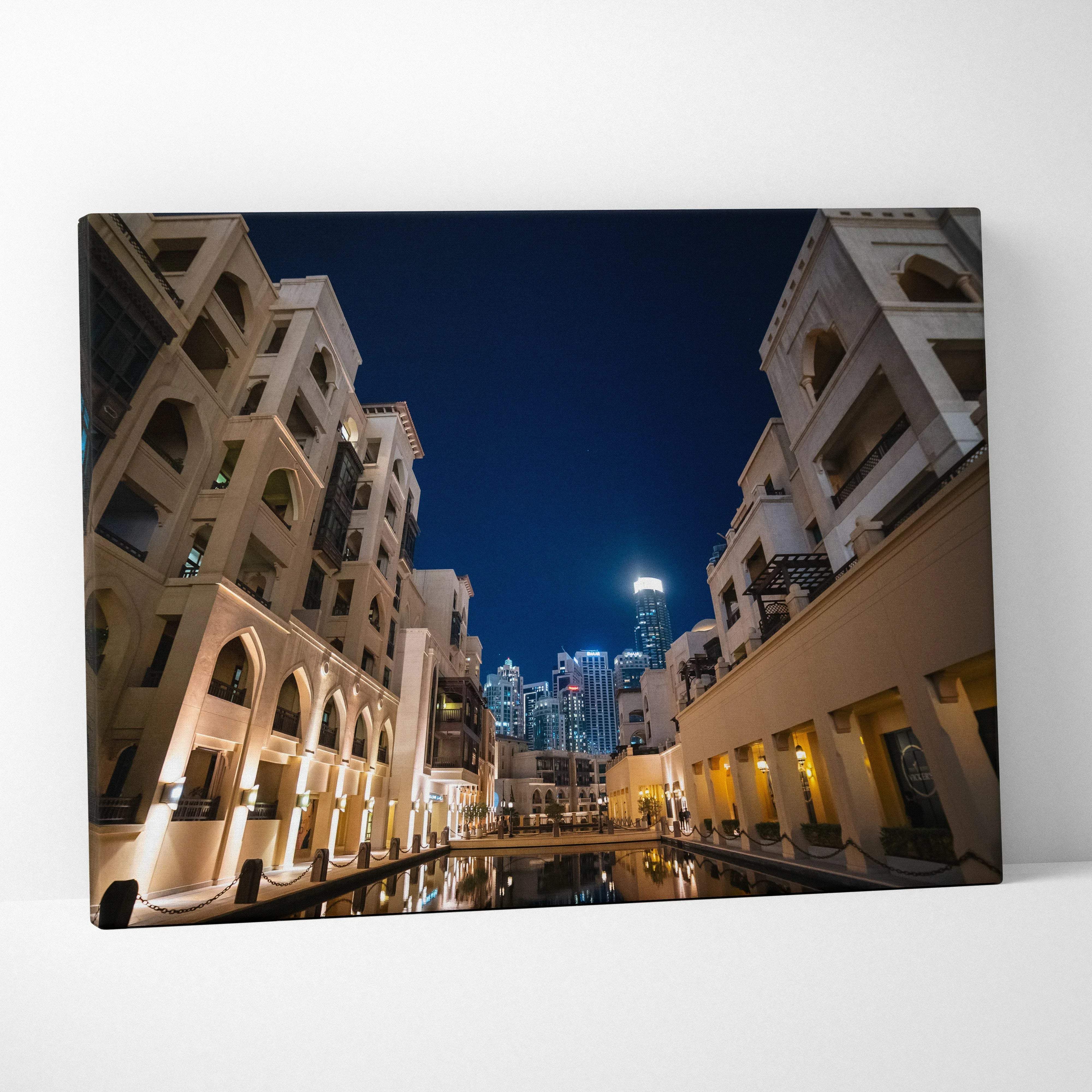 Canvas print of modern architecture night cityscape with warm beige lighting and blue urban skyline over reflective waterway