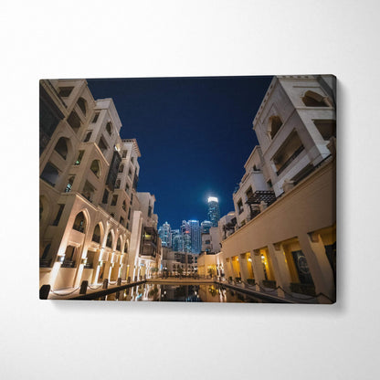 Modern architecture canvas wall art featuring illuminated buildings at night with reflections in water.