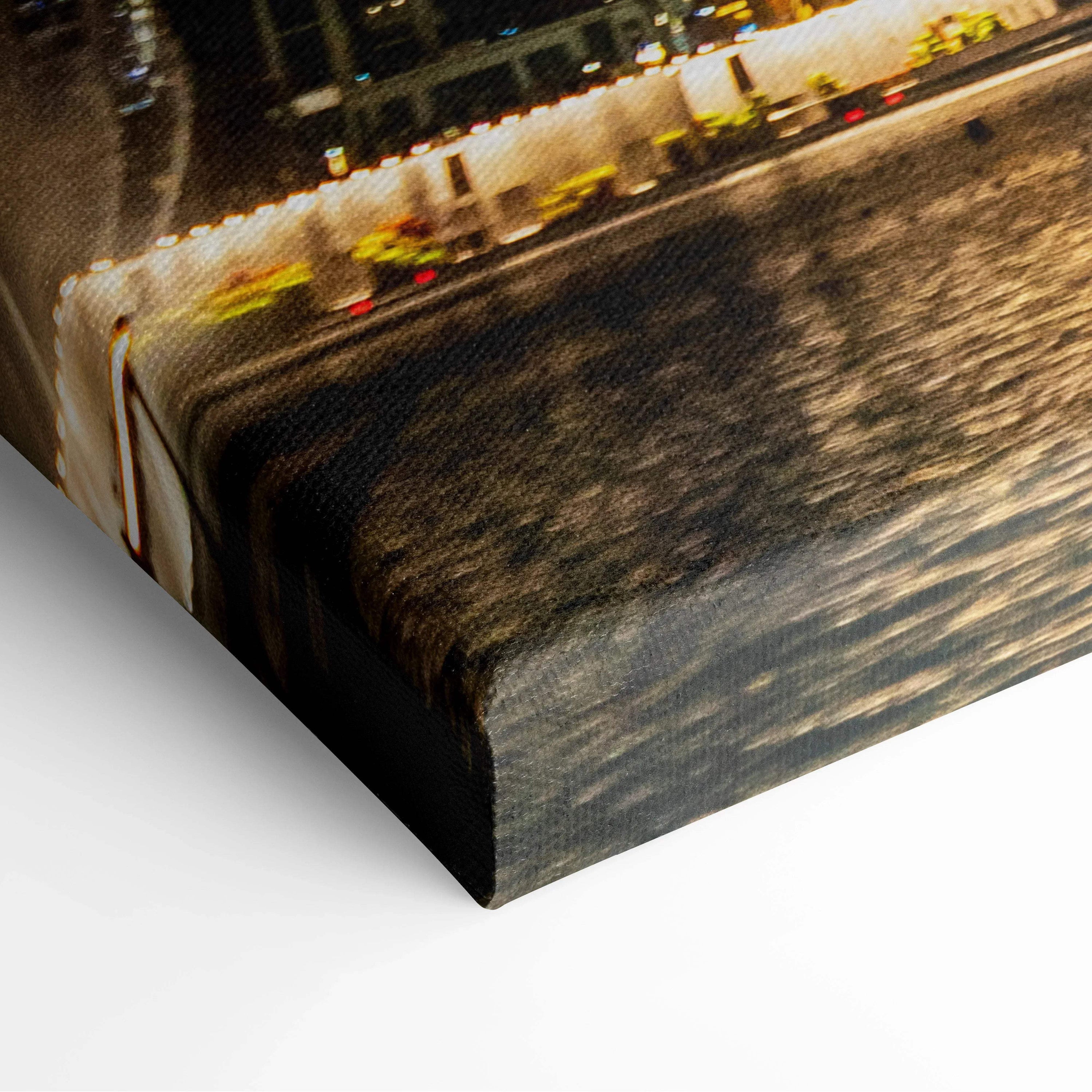 Close-up of wrapped canvas wall art featuring illuminated architectural buildings reflected on water at night.