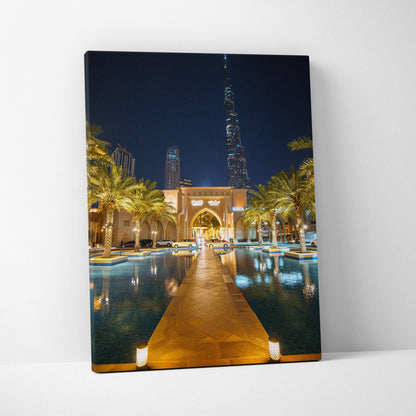 Vertical canvas art depicting illuminated urban architecture and palm trees reflecting in a nighttime pool.