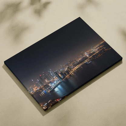 Canvas wall art featuring a nighttime city skyline with illuminated buildings and reflections on water.