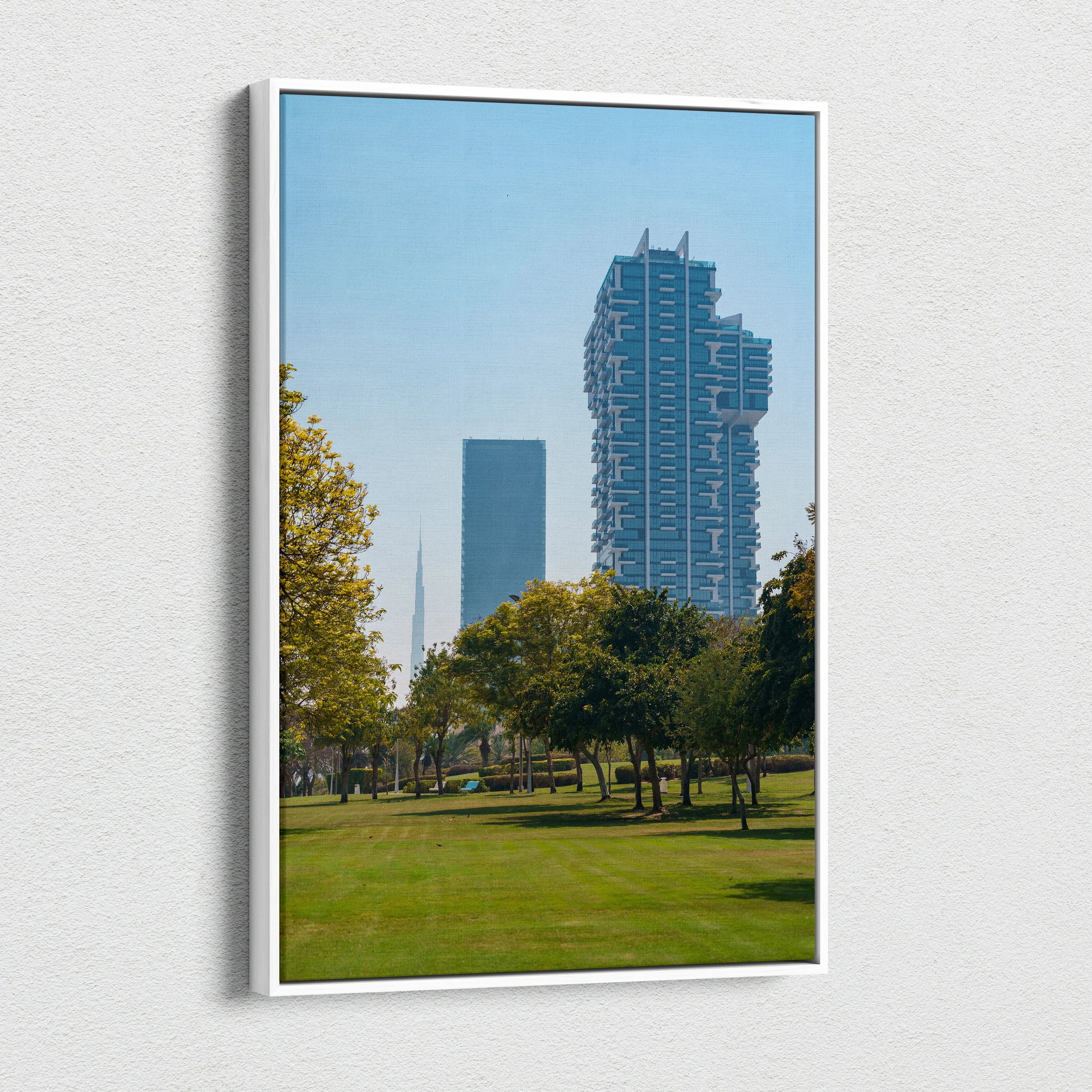 Vertical canvas wall art featuring a blue sky cityscape with modern tall buildings and green park trees.