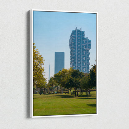 Vertical canvas wall art featuring a blue sky cityscape with modern tall buildings and green park trees.