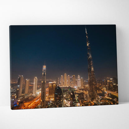 Canvas wall art featuring a nighttime cityscape with illuminated buildings and skyscrapers including a tall, slender tower.