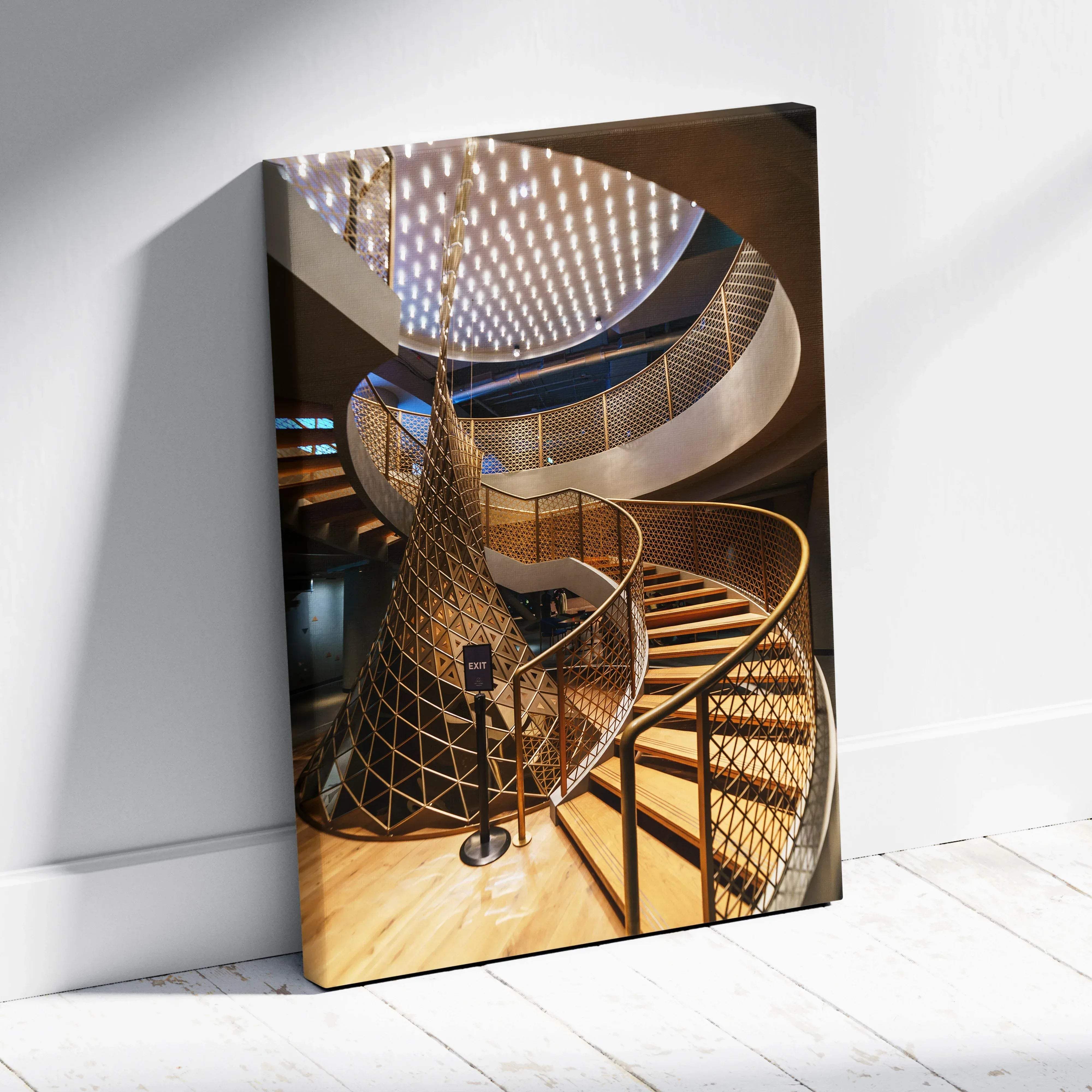 A modern gold-toned spiral staircase with geometric lattice railings and warm wooden steps in an elegant interior
