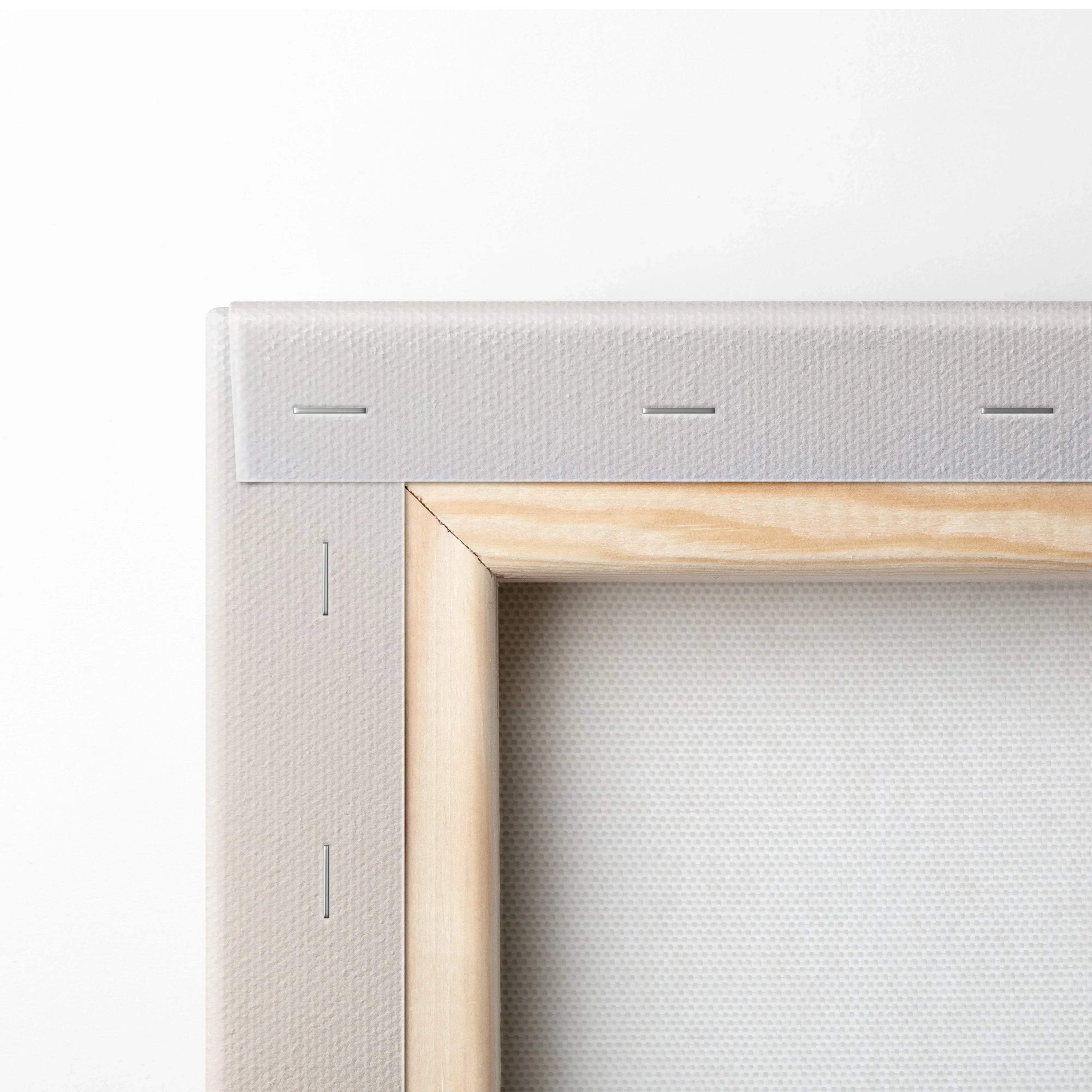 Close-up of beige stretched canvas with natural wood frame and visible staples on white fabric backing.