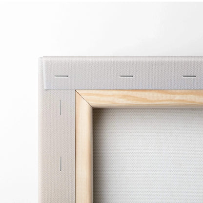 Close-up of beige stretched canvas with natural wood frame and visible staples on white fabric backing.